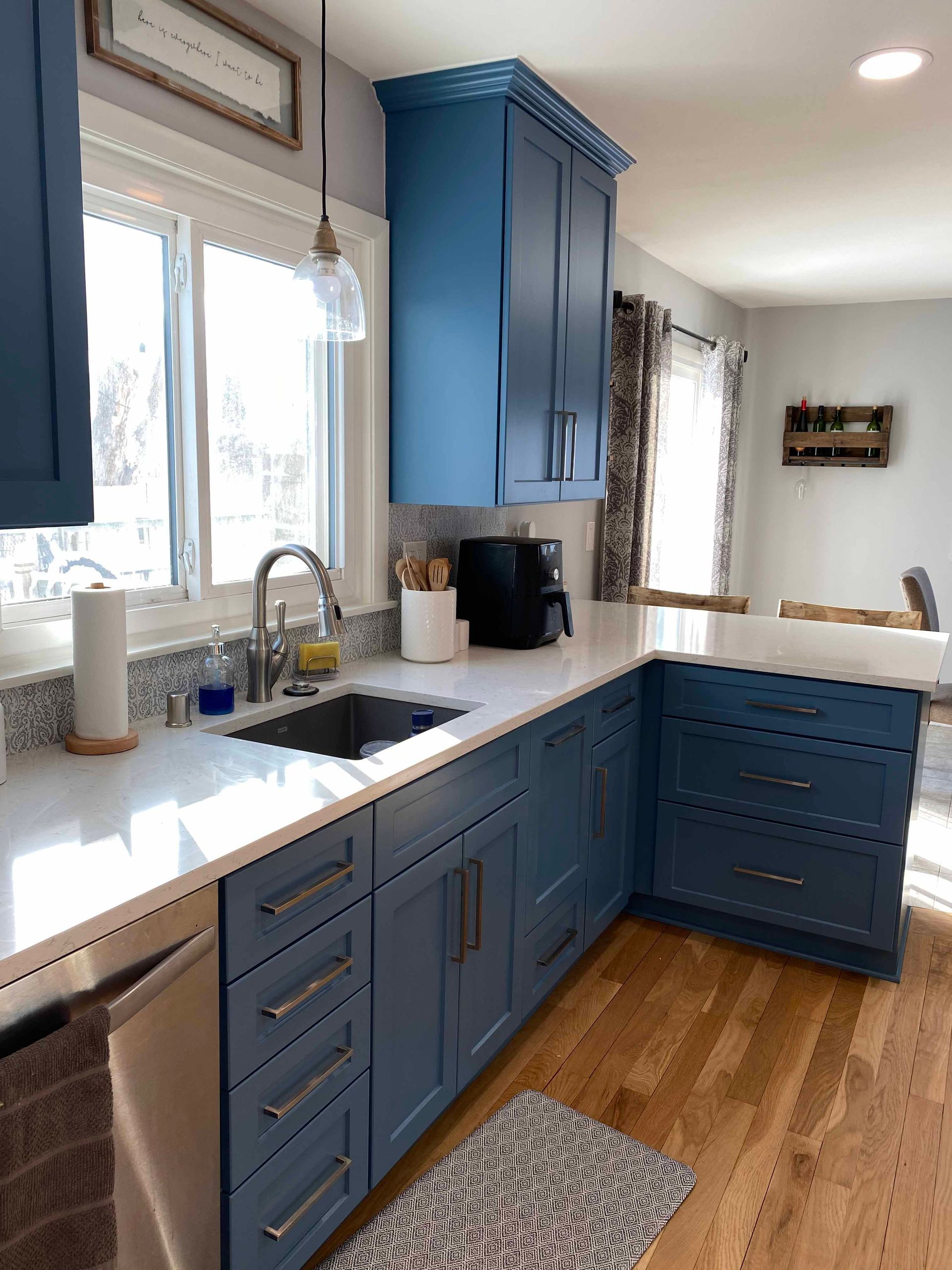 A kitchen with blue cabinets and white counter tops.