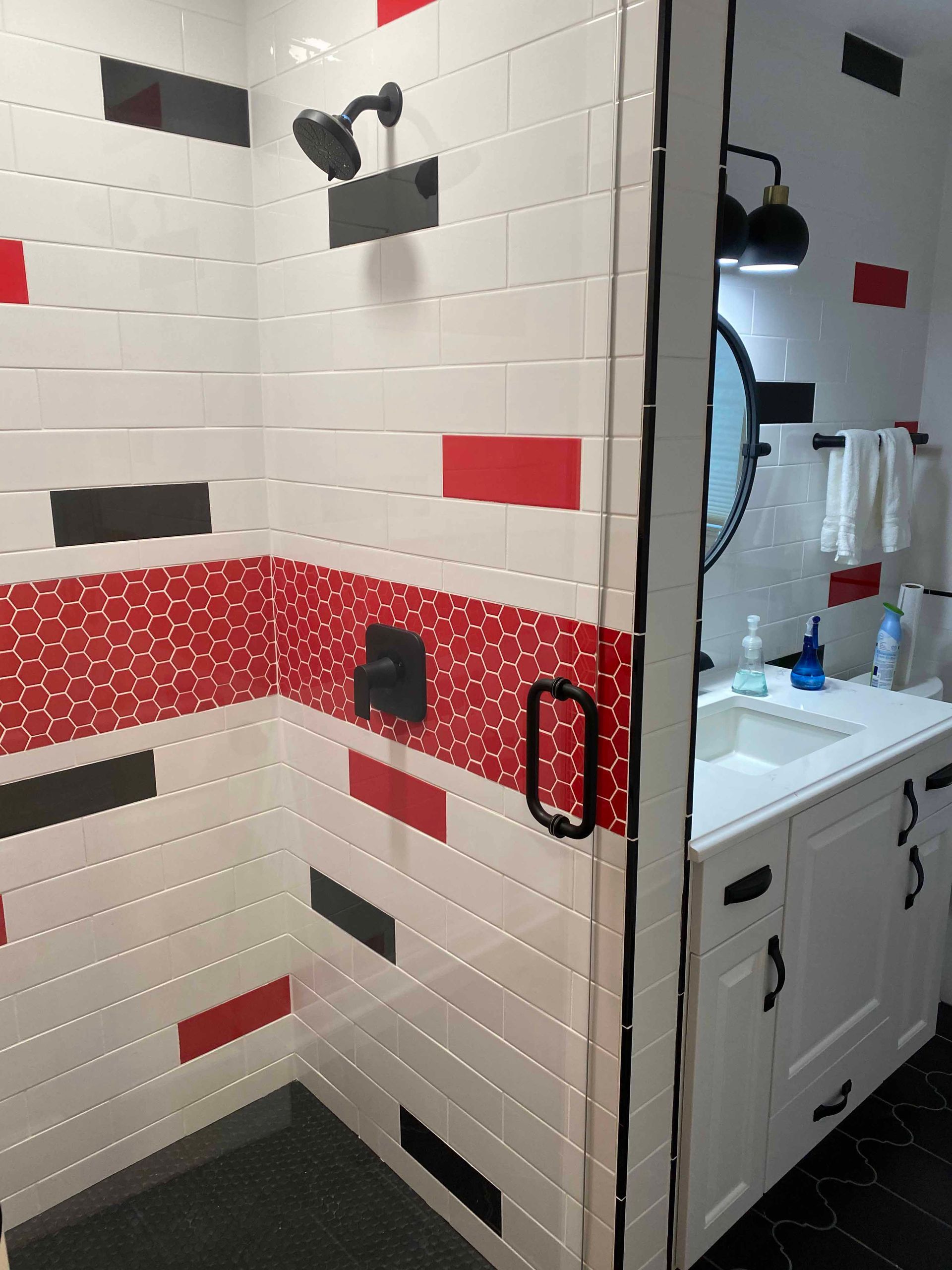 A bathroom with red , black and white tiles and a walk in shower.