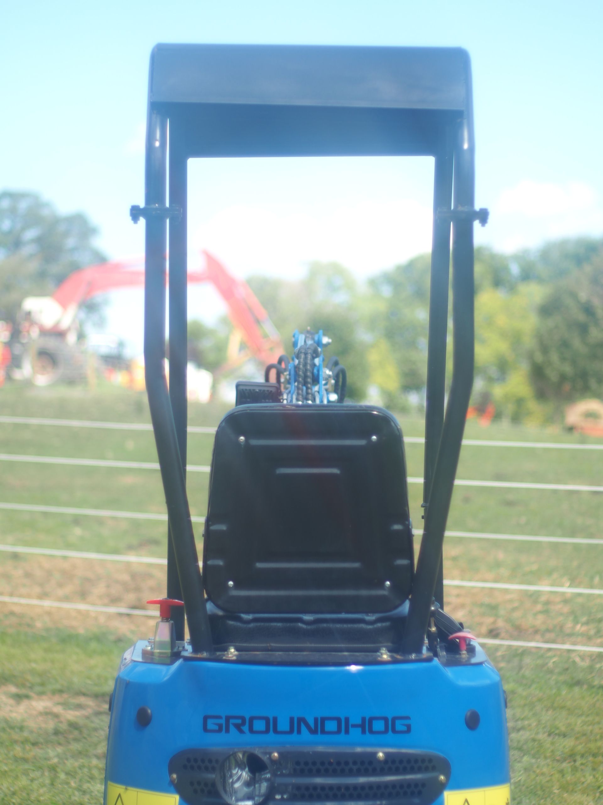 Blue Groundhog construction machine with a black roll cage, outdoors on grass.