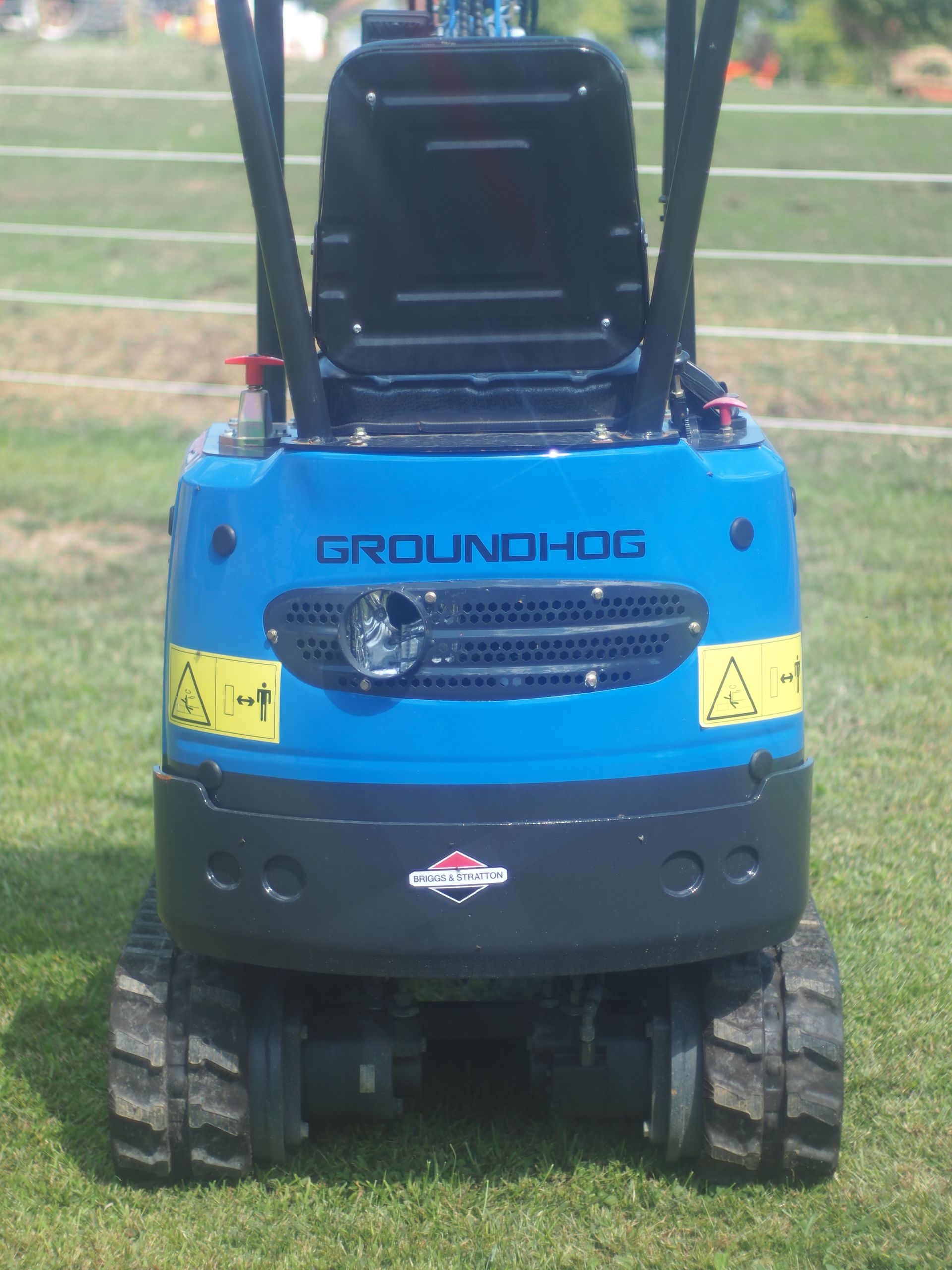 Blue Groundhog mini excavator on grass, rear view.