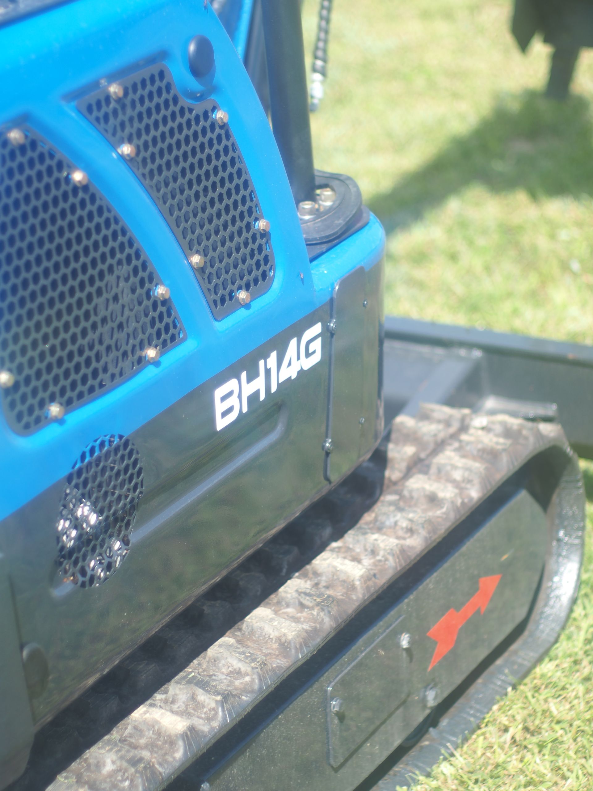 Blue and black BH14G mini excavator on grass.