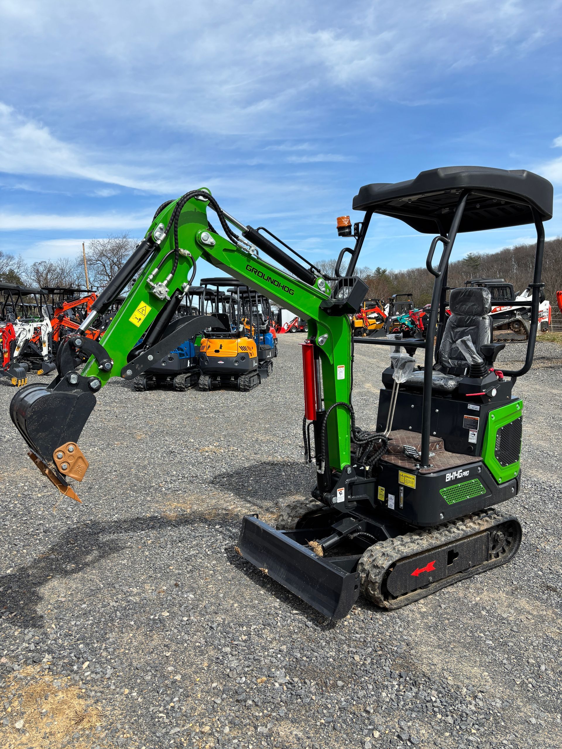 Green and black mini excavator on gravel, with a black canopy.