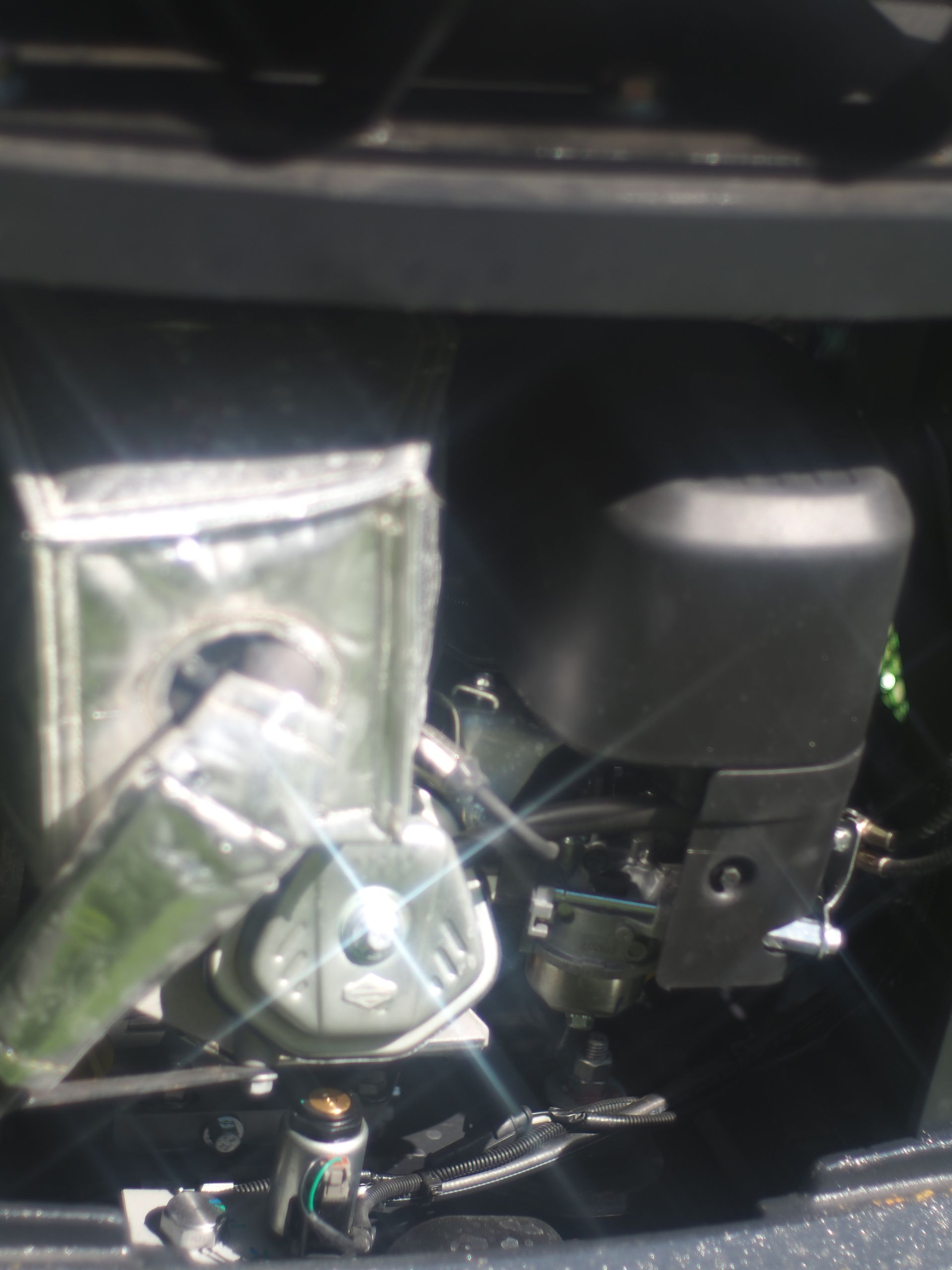 Close-up of a small engine with metallic covering, black air filter, and wiring.