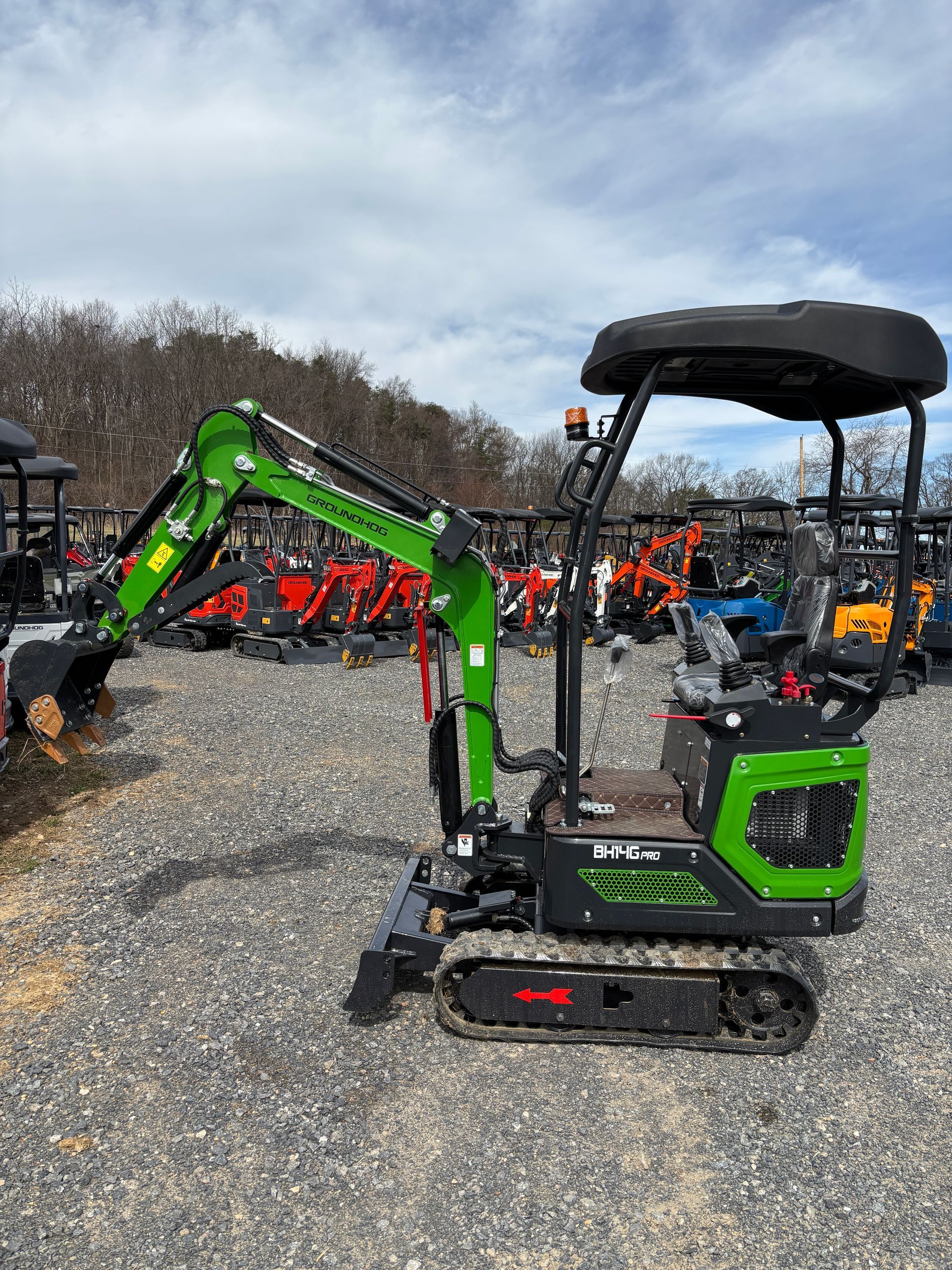 Green and black mini excavator on gravel, outdoors.