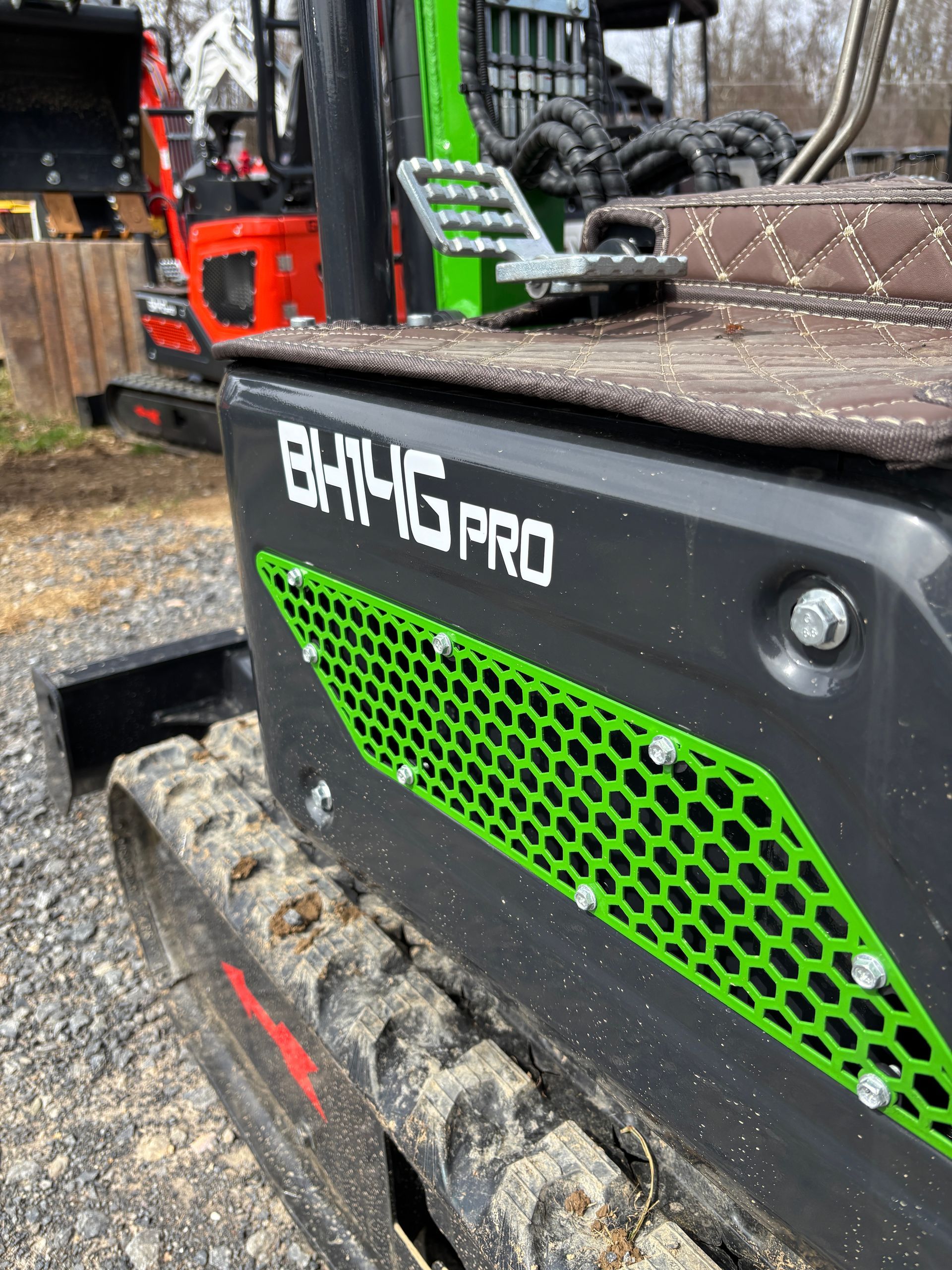 Black and green BHT4G PRO mini excavator with a muddy track in an outdoor setting.