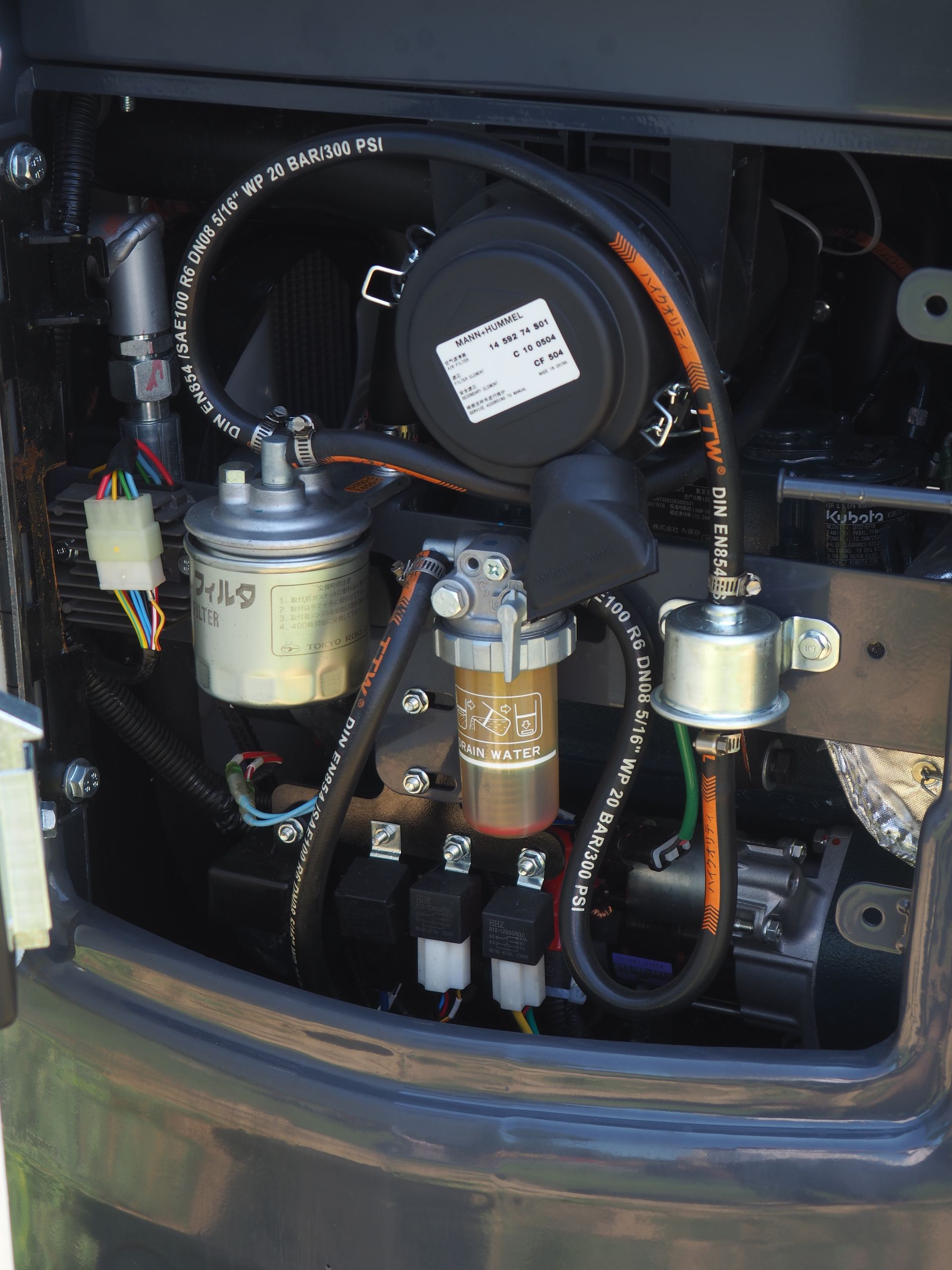 Close-up of a generator's internal components, featuring filters, hoses, and electrical wiring, with a dark background.