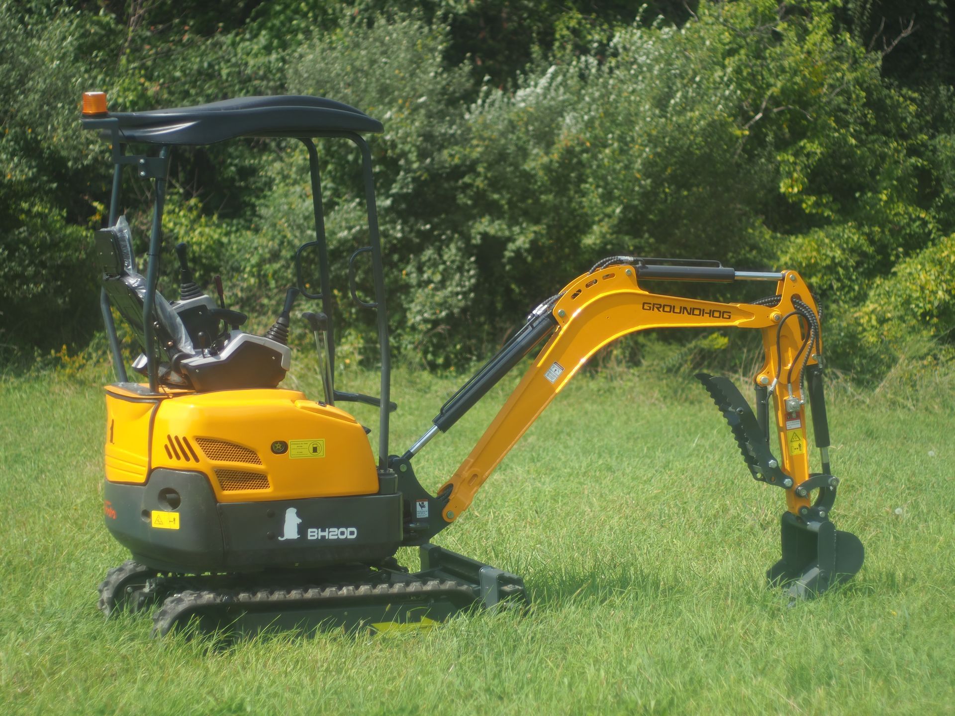 Yellow mini excavator on grass.