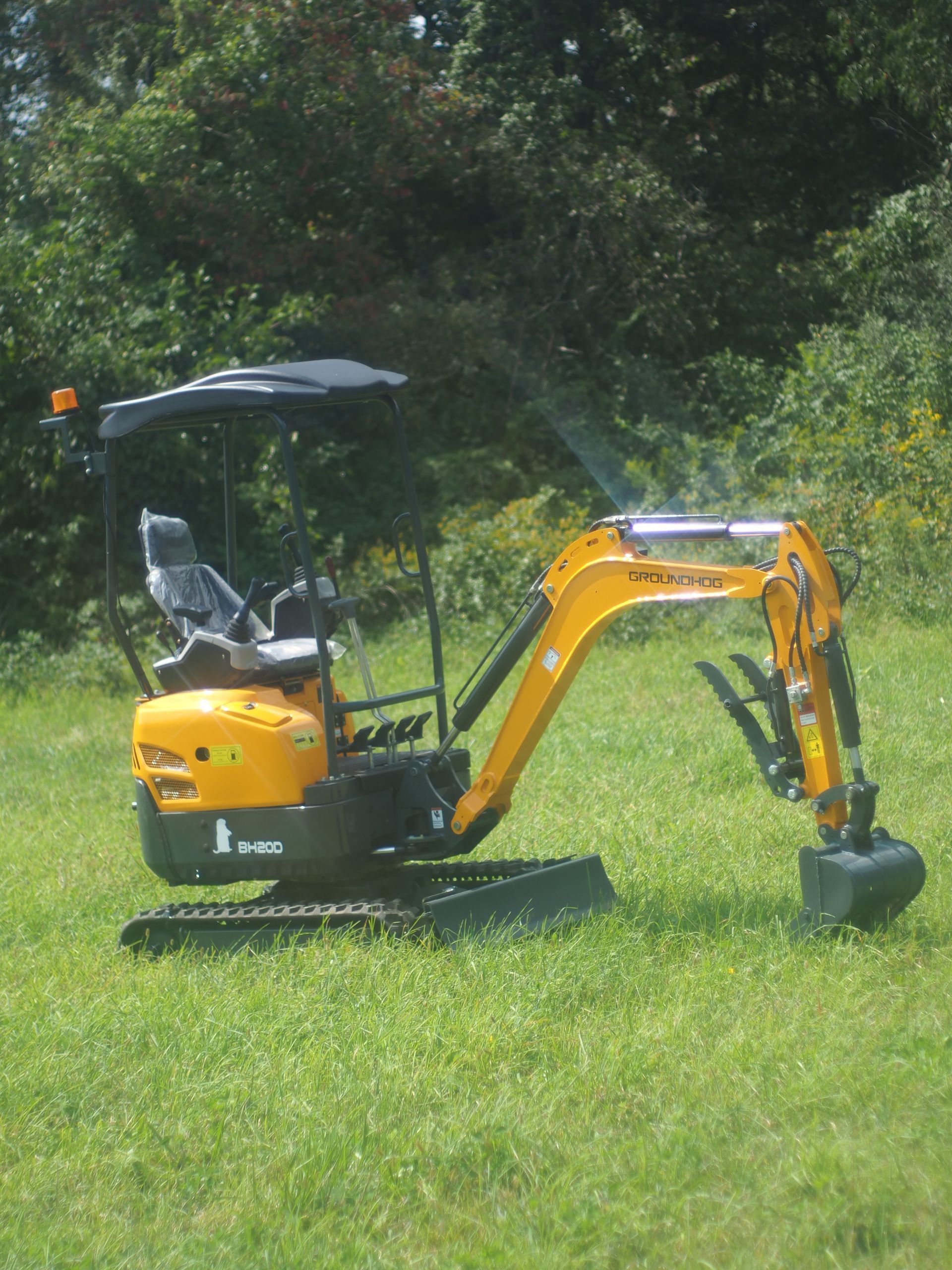 Yellow mini excavator on grassy field.