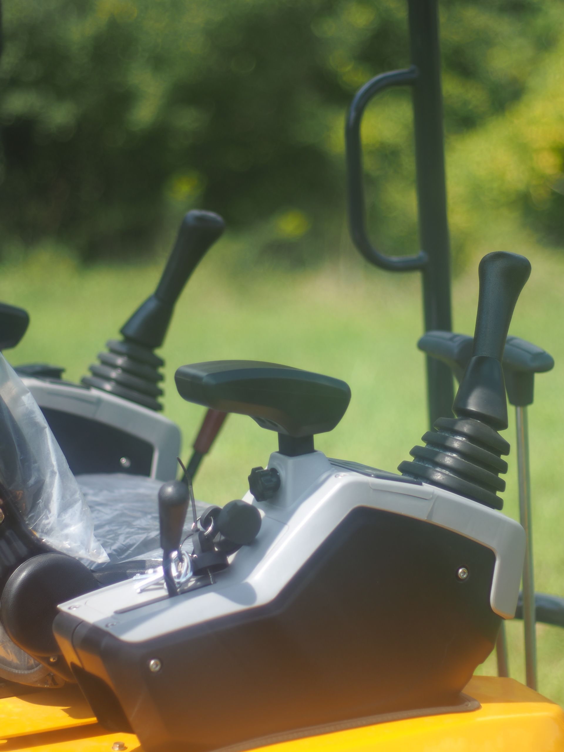 Control panel of a yellow excavator with black joysticks, outdoors.