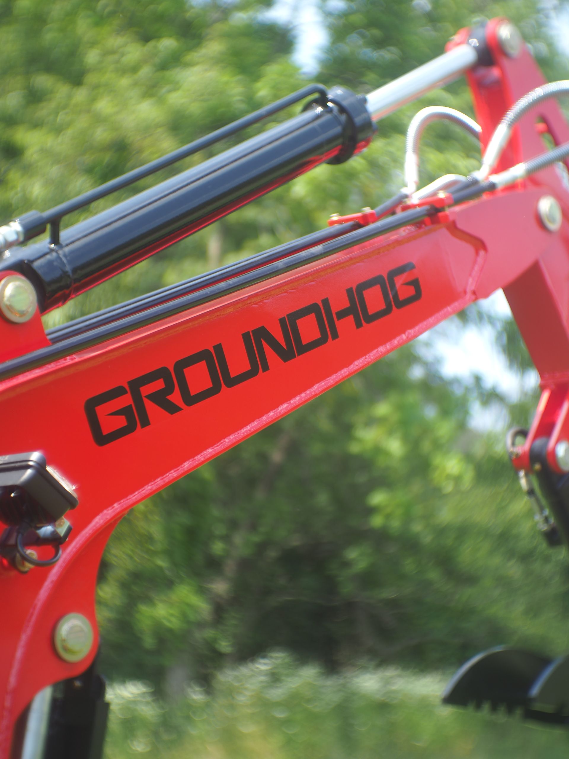 Red Groundhog excavator arm with black text and a hydraulic cylinder.