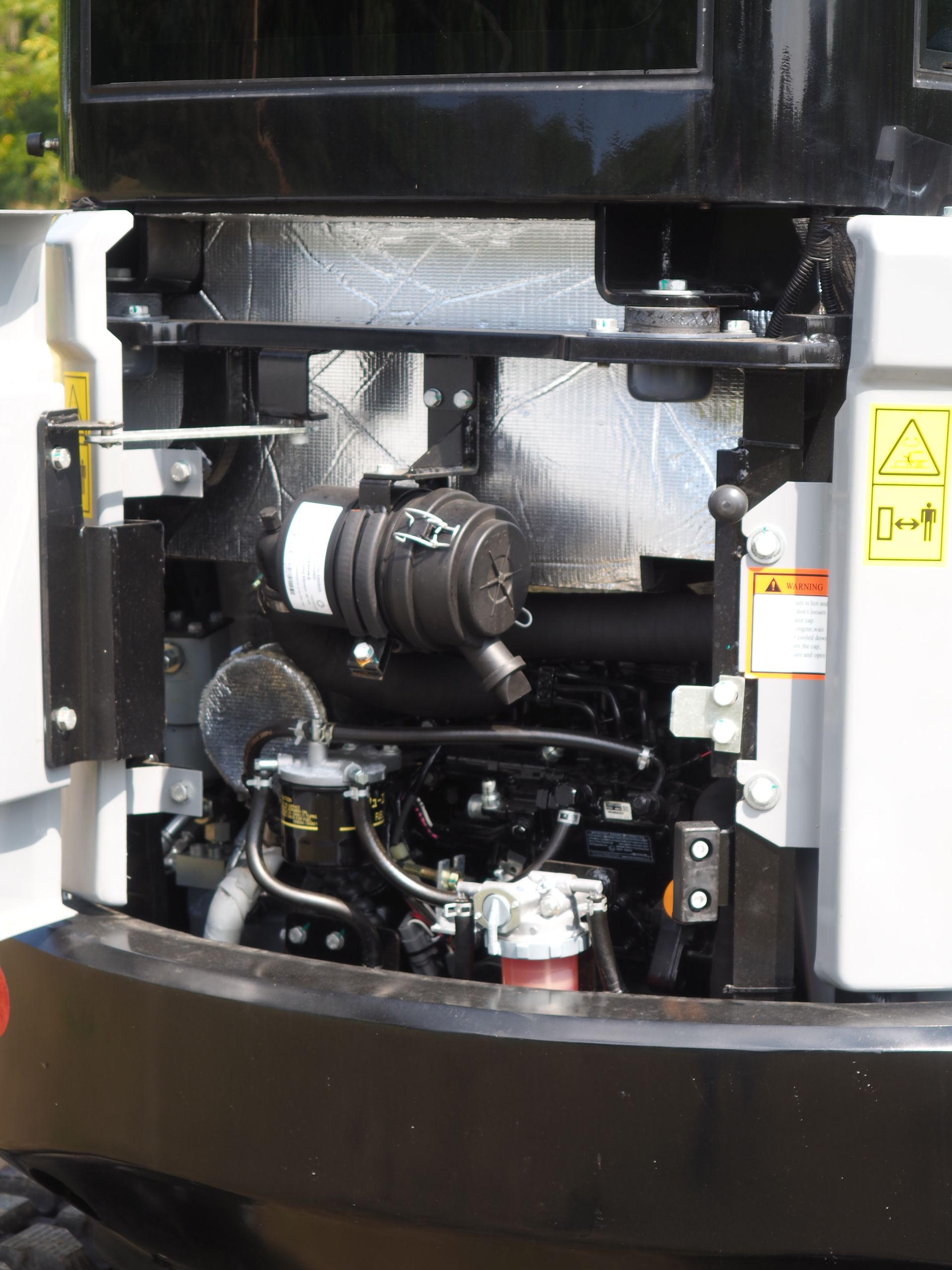 Rear view of a Bobcat mini excavator's engine compartment, showing the engine, air filter, and surrounding components.