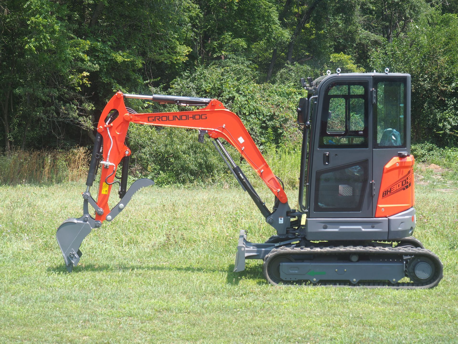 Orange and gray mini excavator on grass.