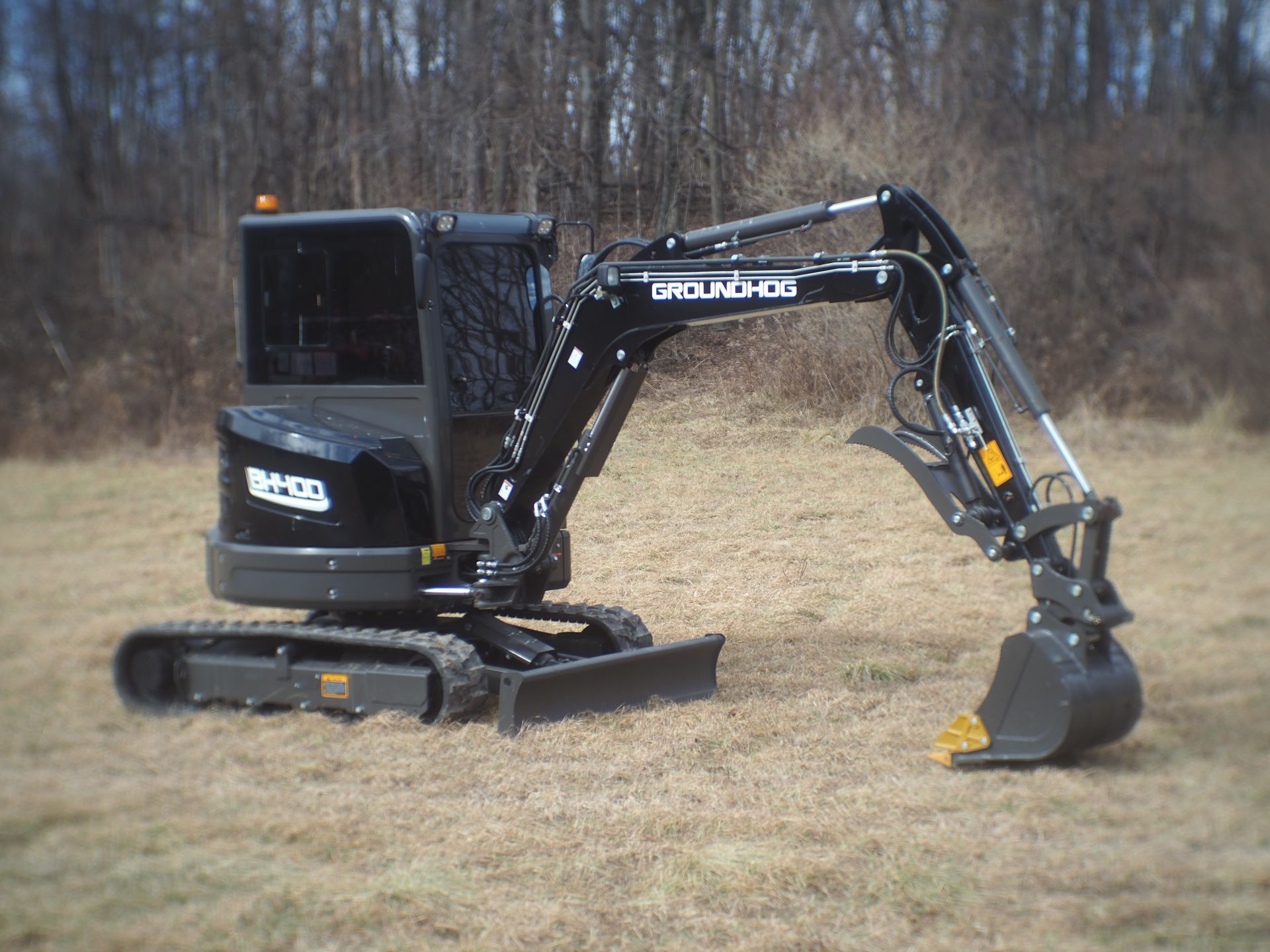 Black mini-excavator on a grassy field.