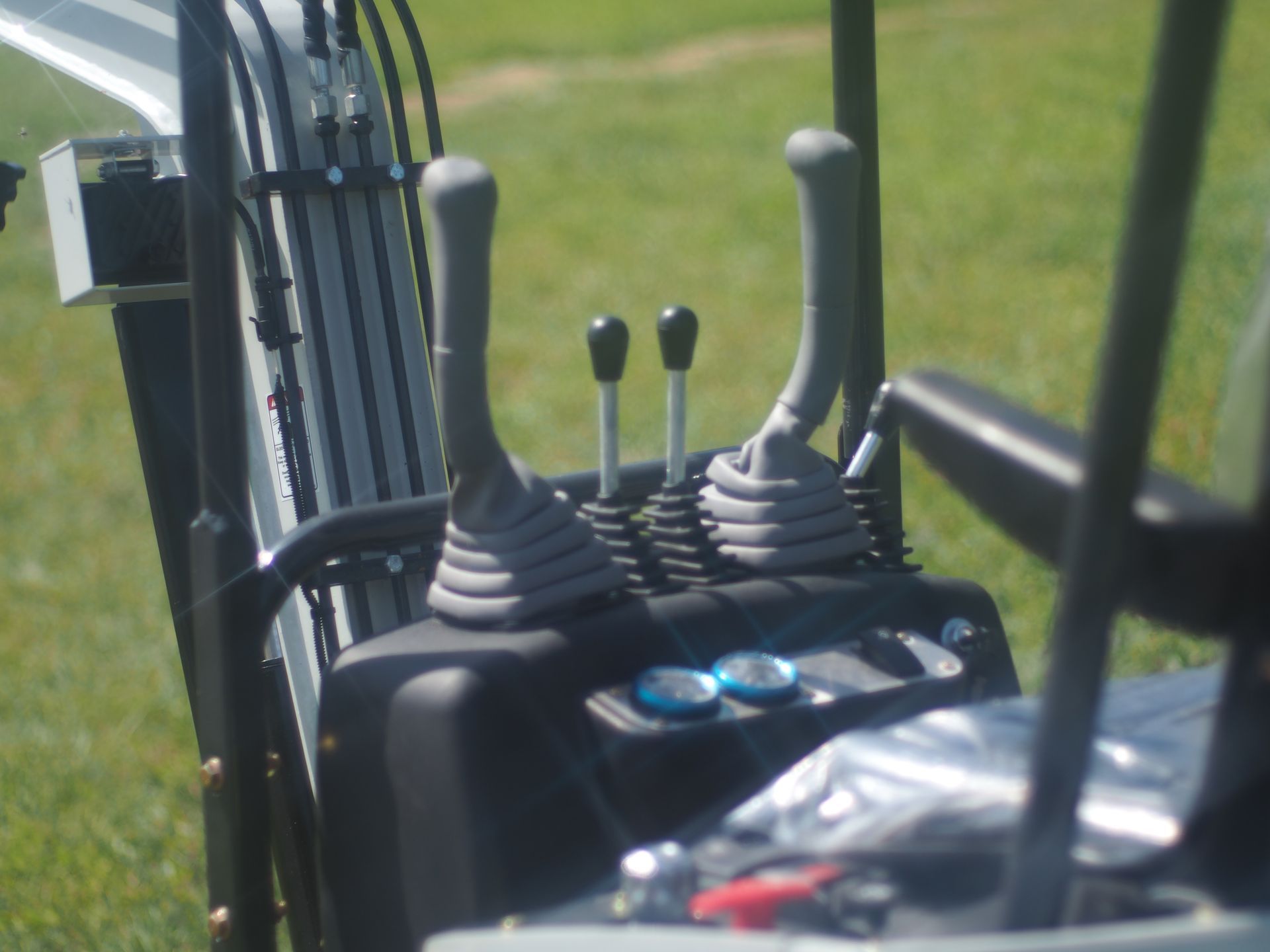 Close-up of an excavator's controls with levers, buttons, and a partial view of the seat.