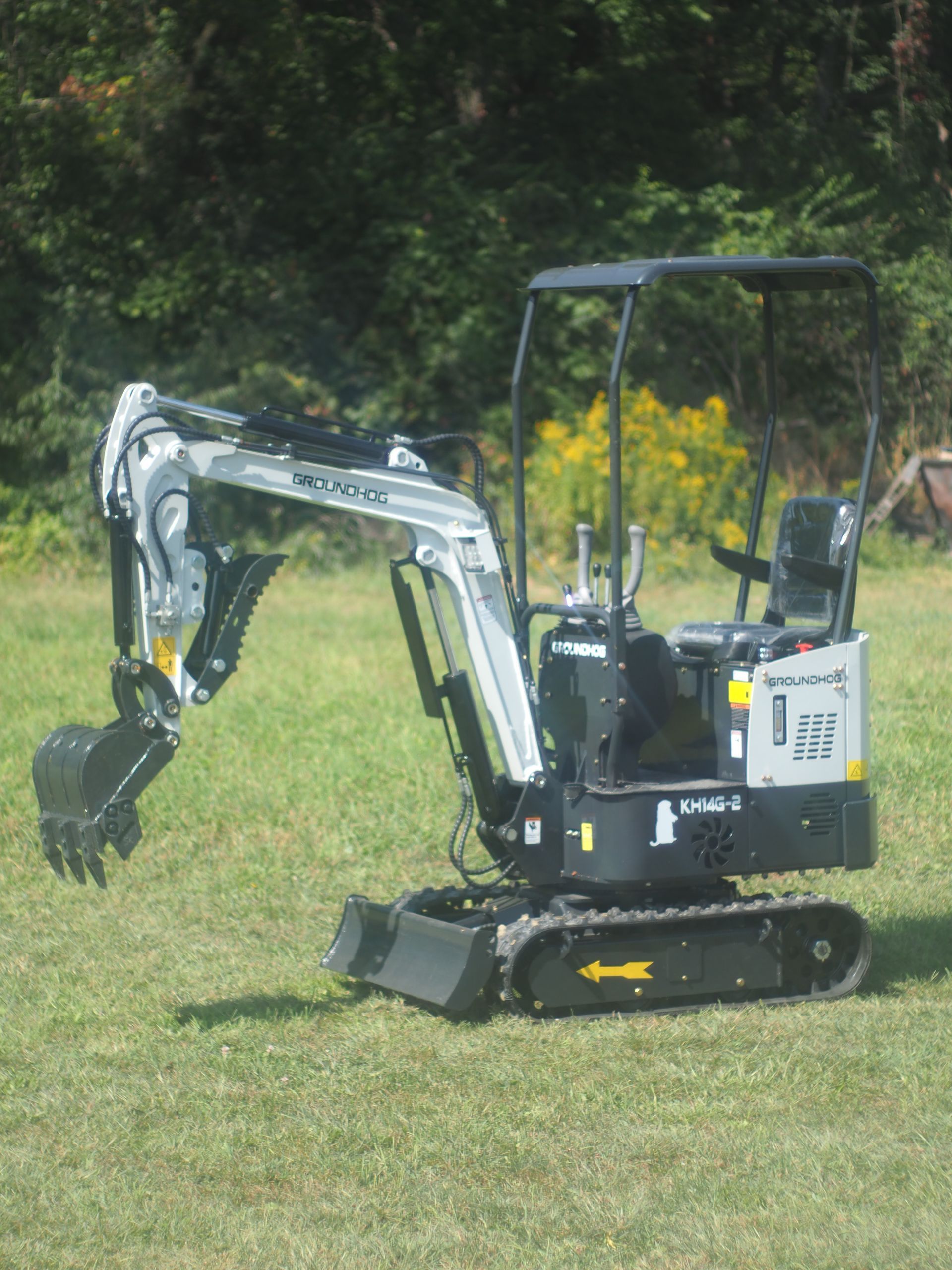 Small silver and black excavator on green grass.