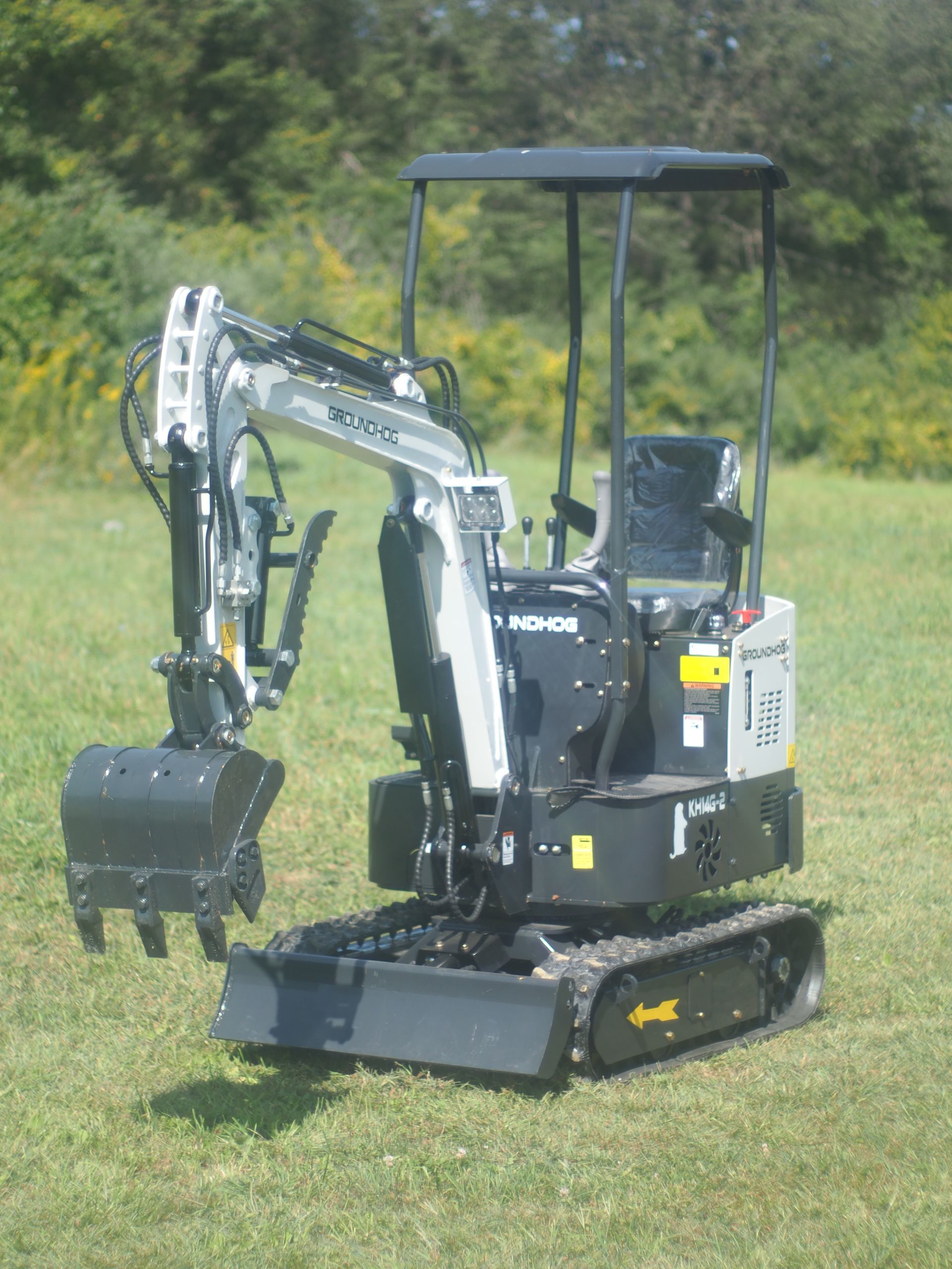 Compact black and gray excavator on grass, with tracks and a bucket attachment.