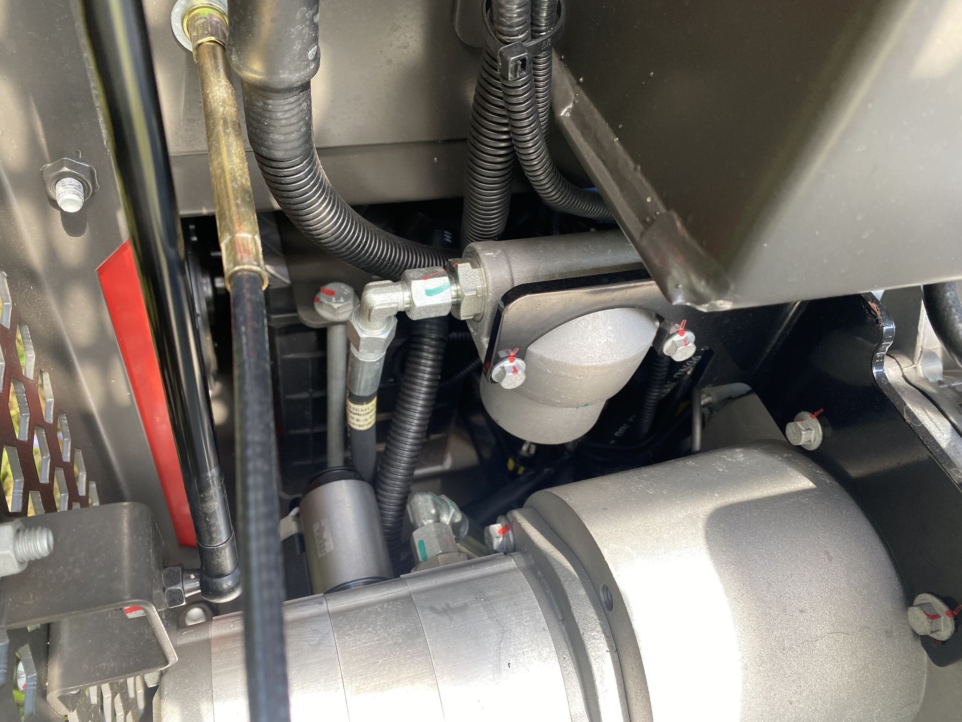 Close-up view of machinery components, including hoses, filter, and metal framework.