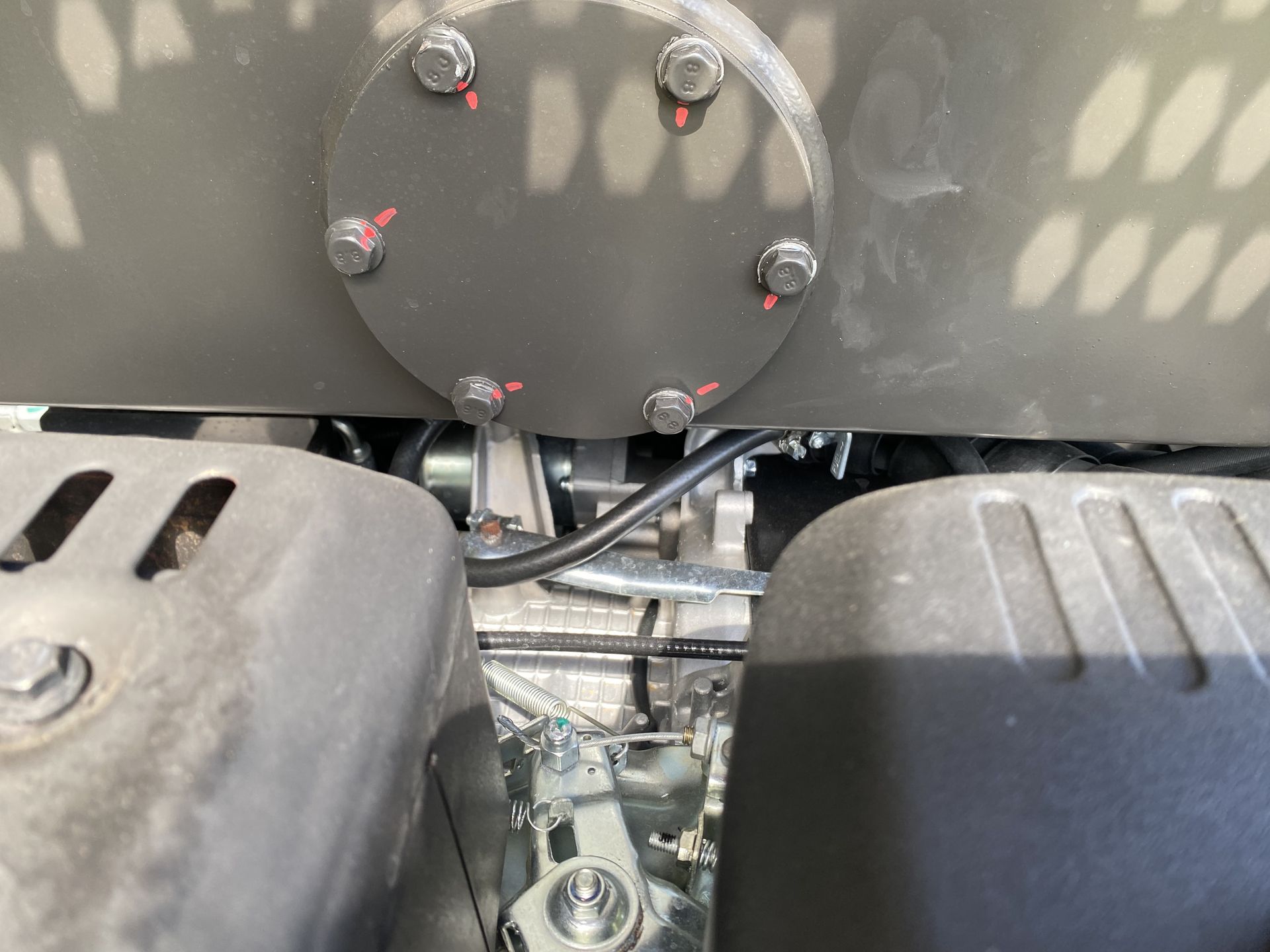 Gray machinery components, bolts, and black cable visible.