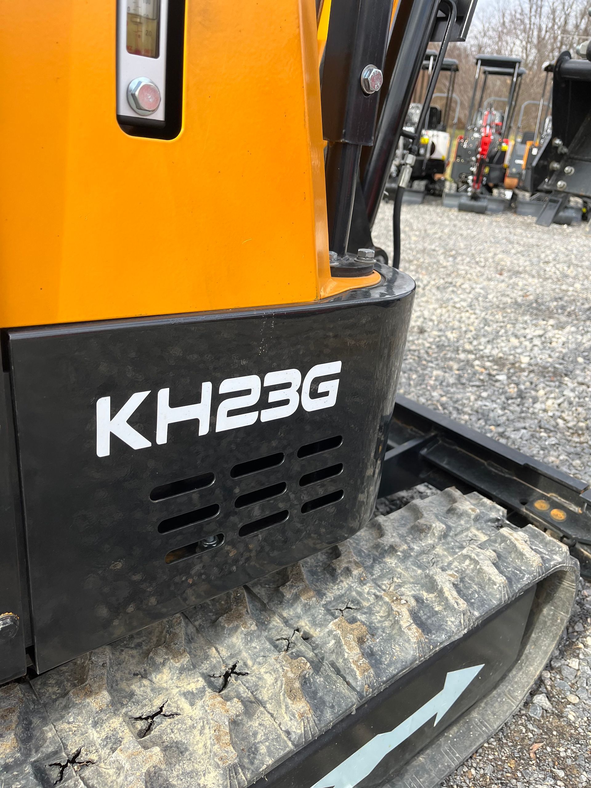Close-up of a yellow and black KH23G mini excavator on a track, outdoors.