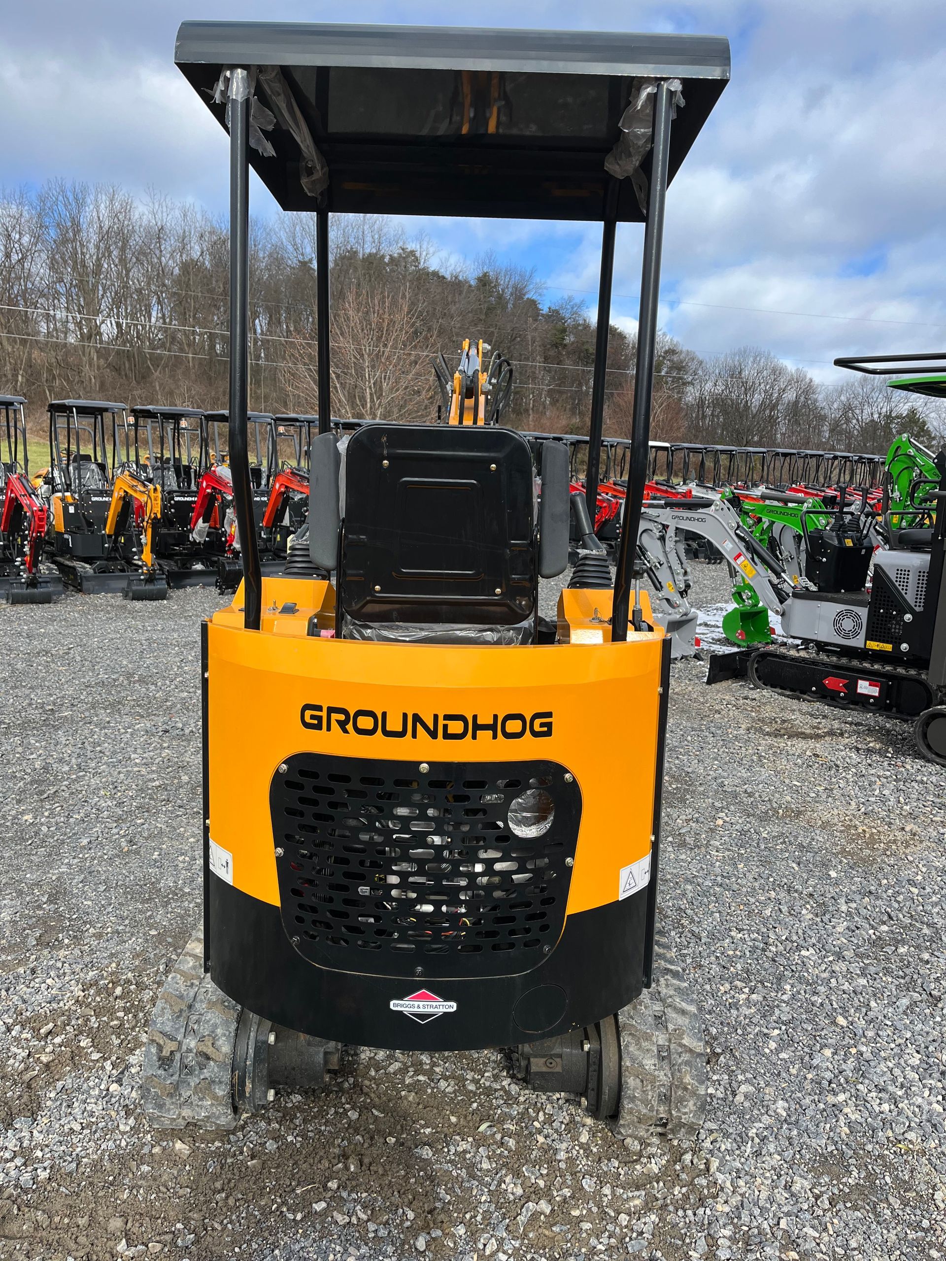 Yellow and black Groundhog mini skid steer with canopy, on a gravel lot.