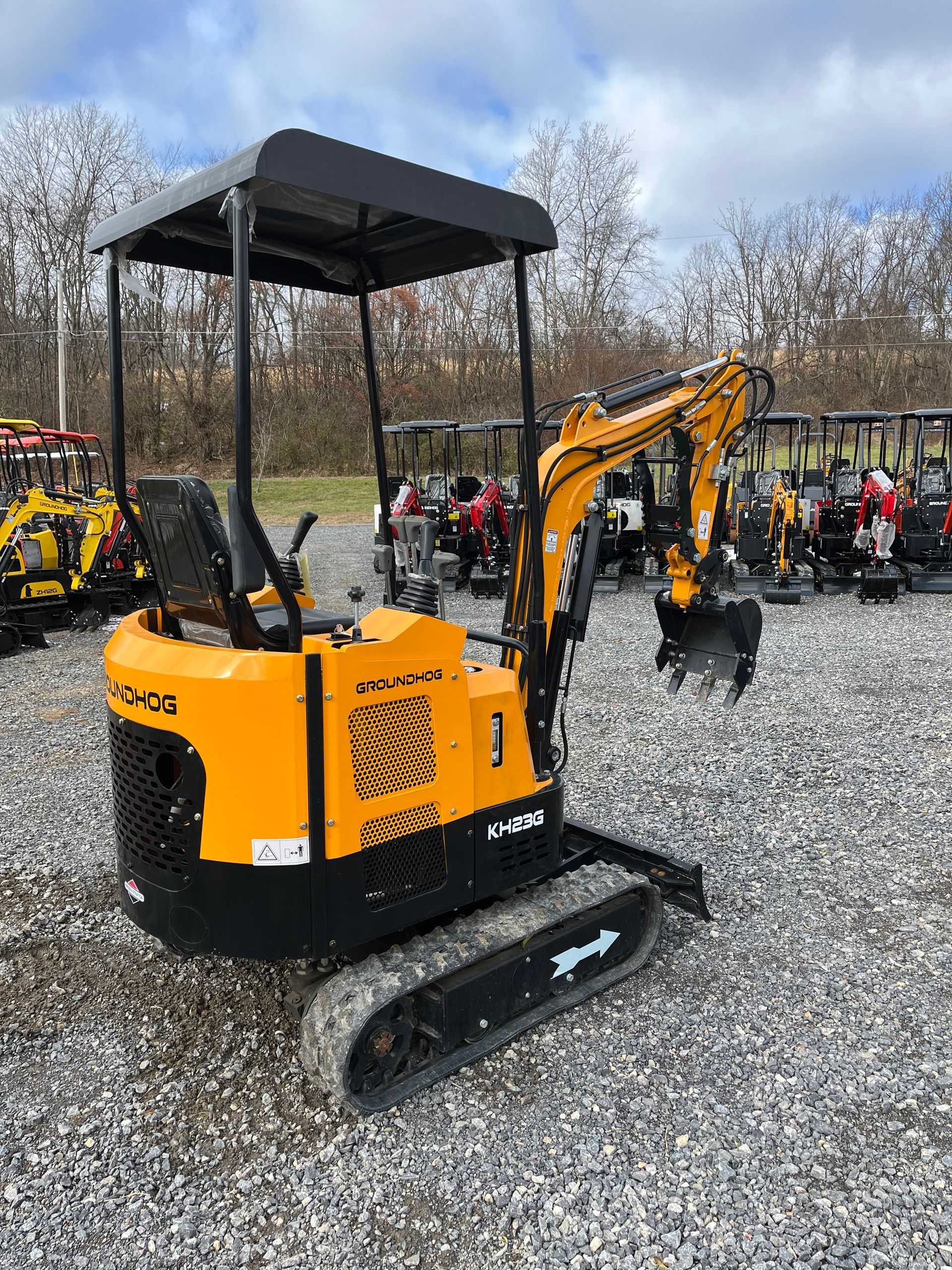 Yellow Kubota mini-excavator with black tracks and canopy, outdoors on gravel.