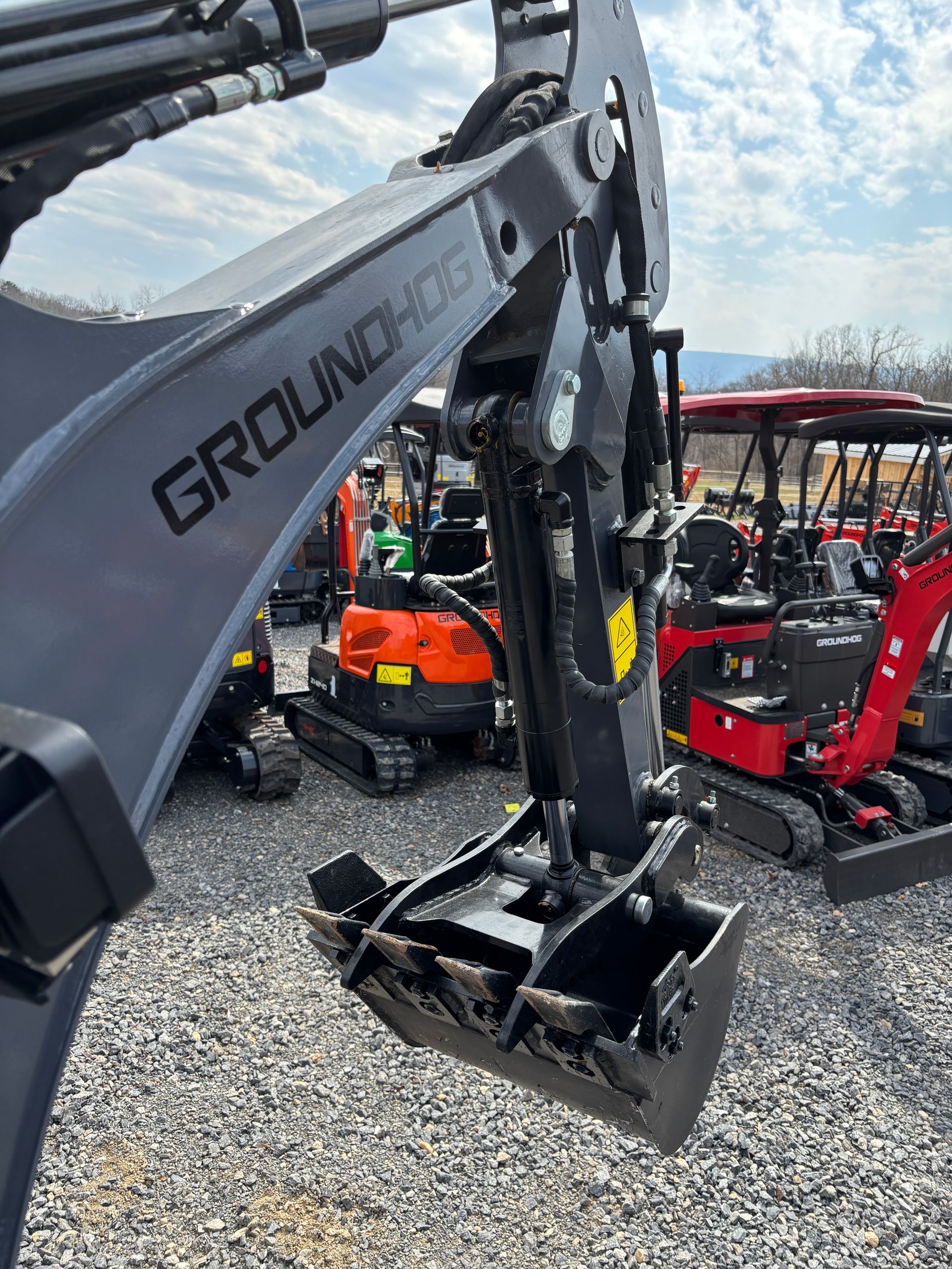 Gray and black GroundHog excavator bucket; parked at a lot with other mini-excavators.