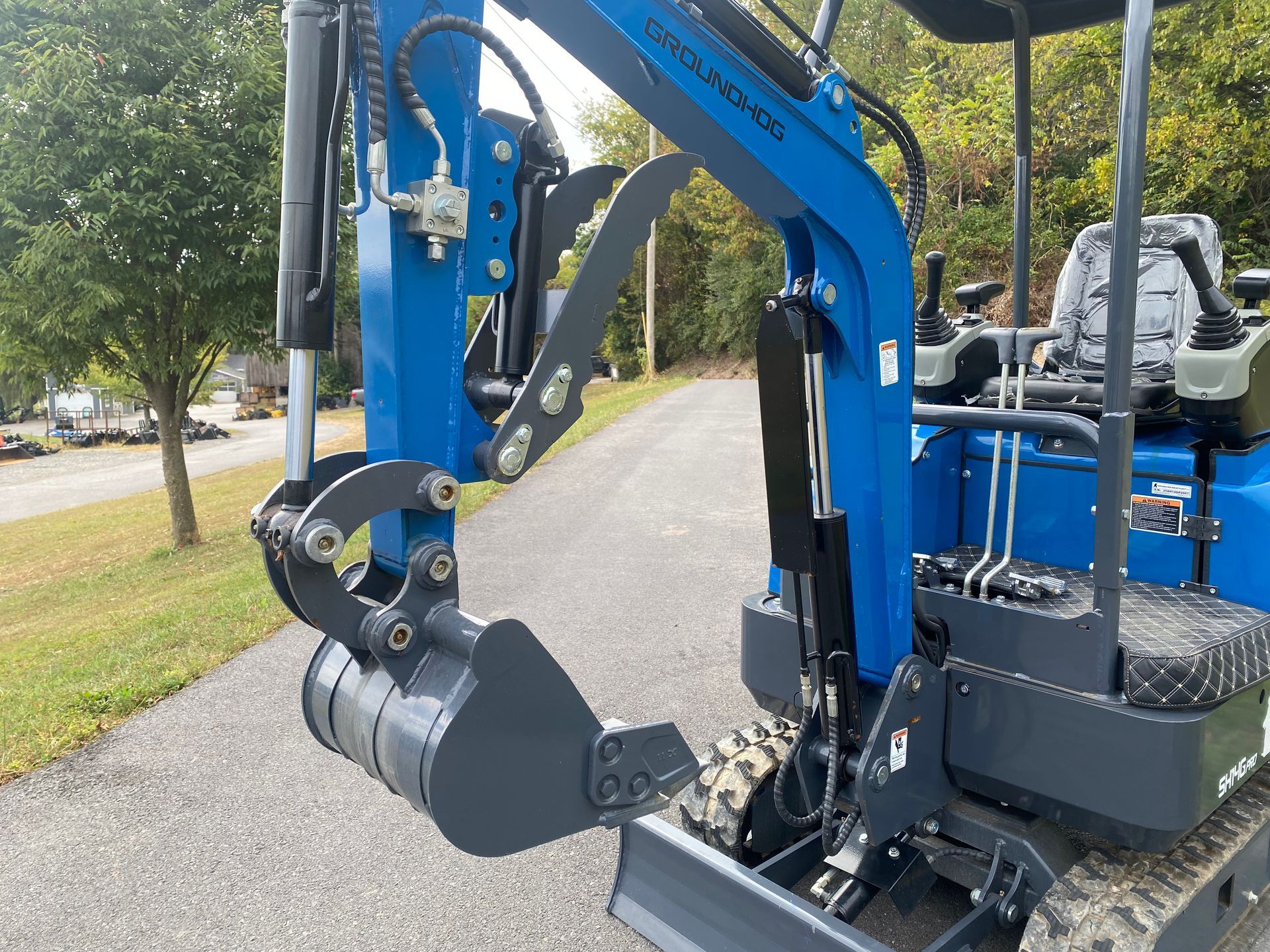 Blue and gray mini excavator on asphalt, ready to dig.