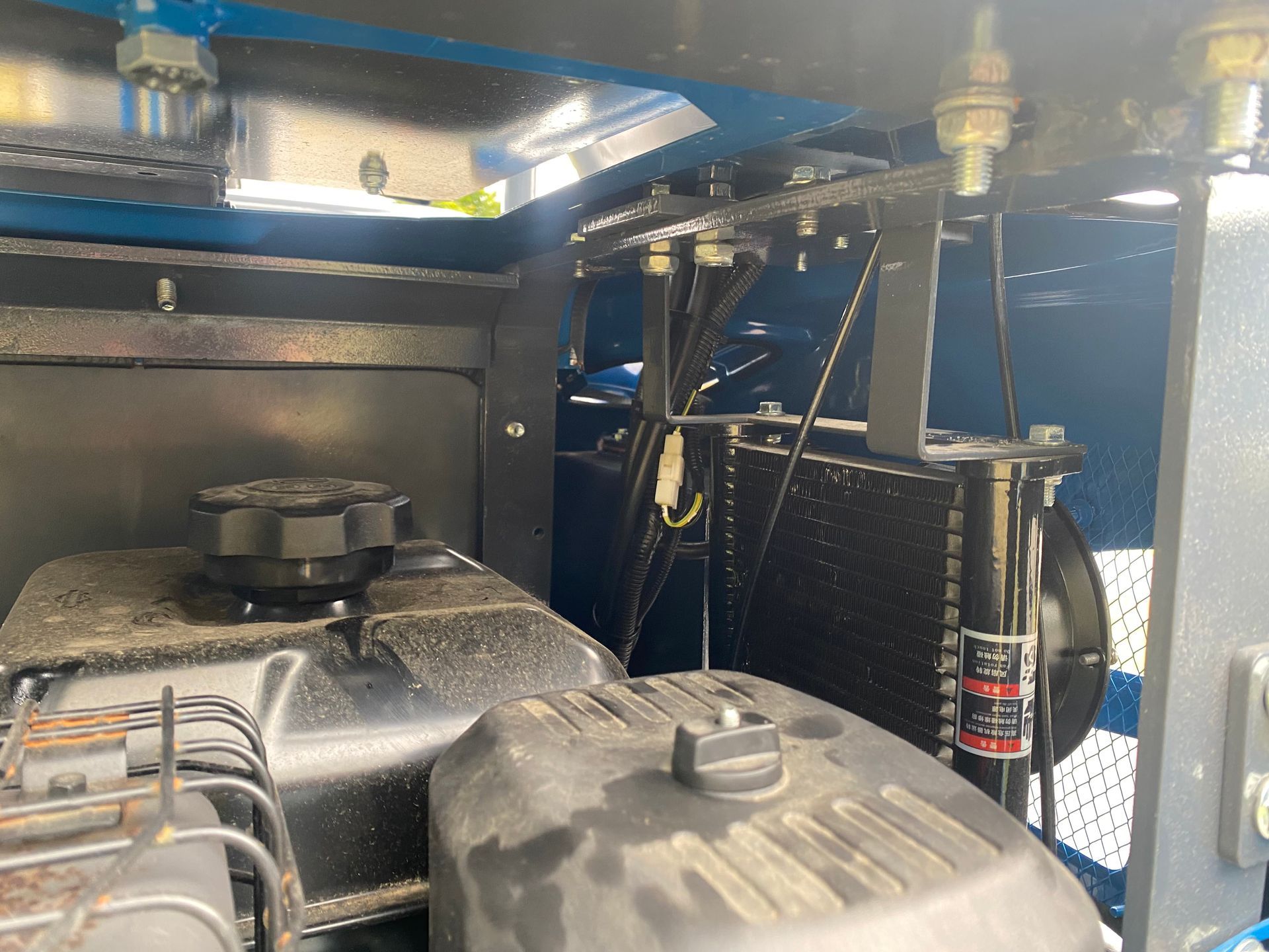 Internal view of an engine with black covers, surrounded by blue and black metal components.