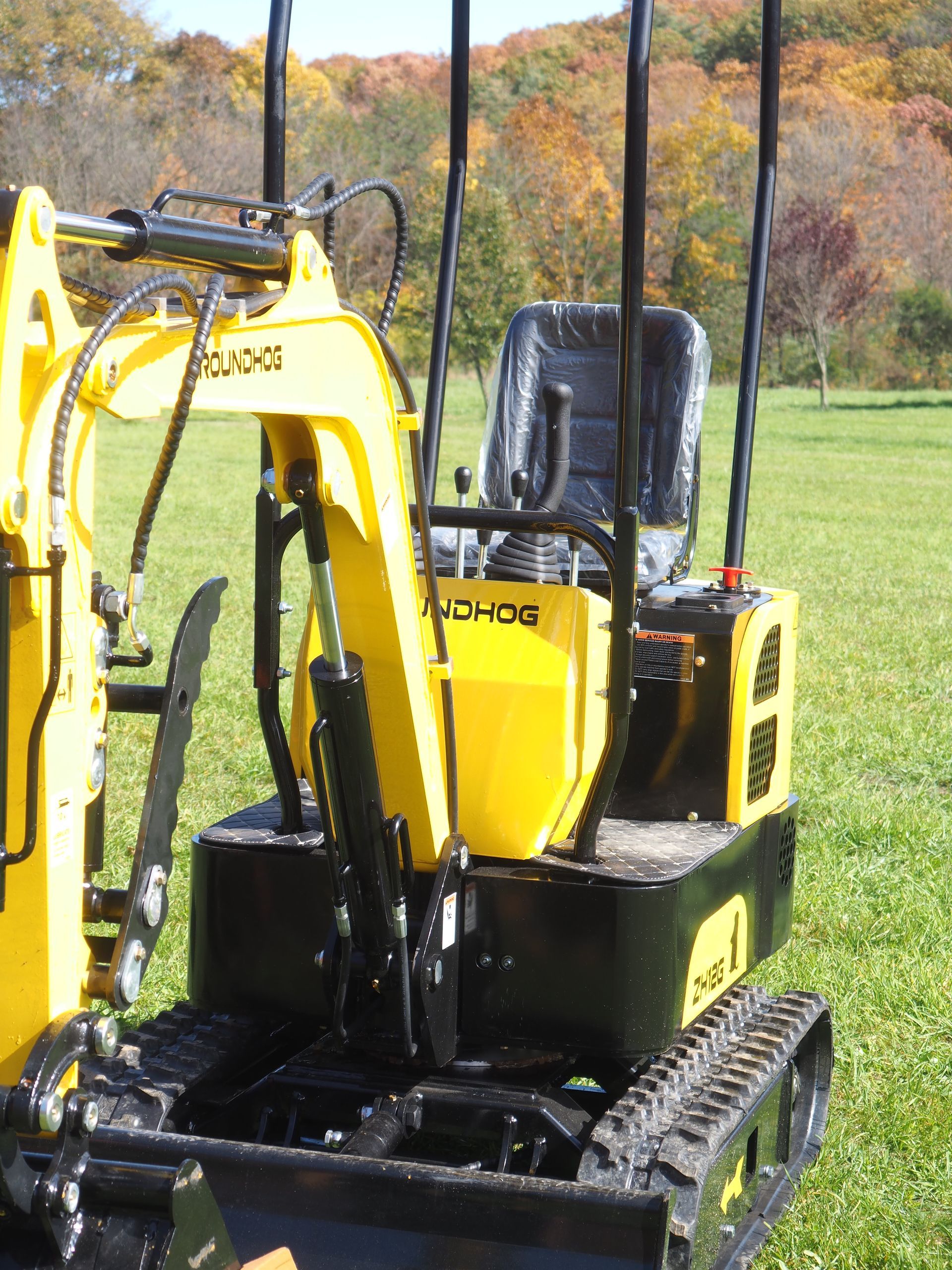 Yellow and black mini excavator on a grassy field.