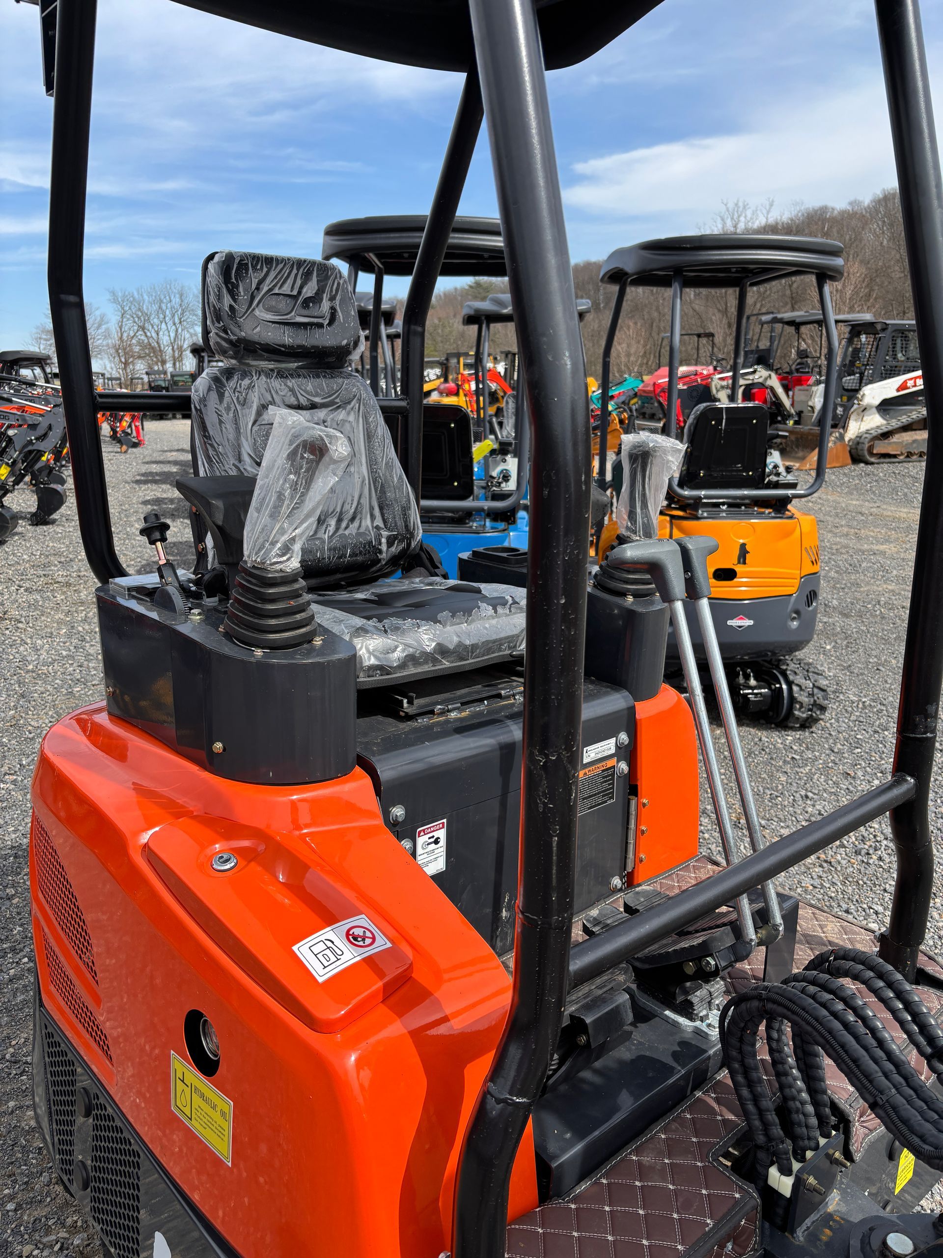 Orange Kubota mini excavator seat and controls, outdoors.