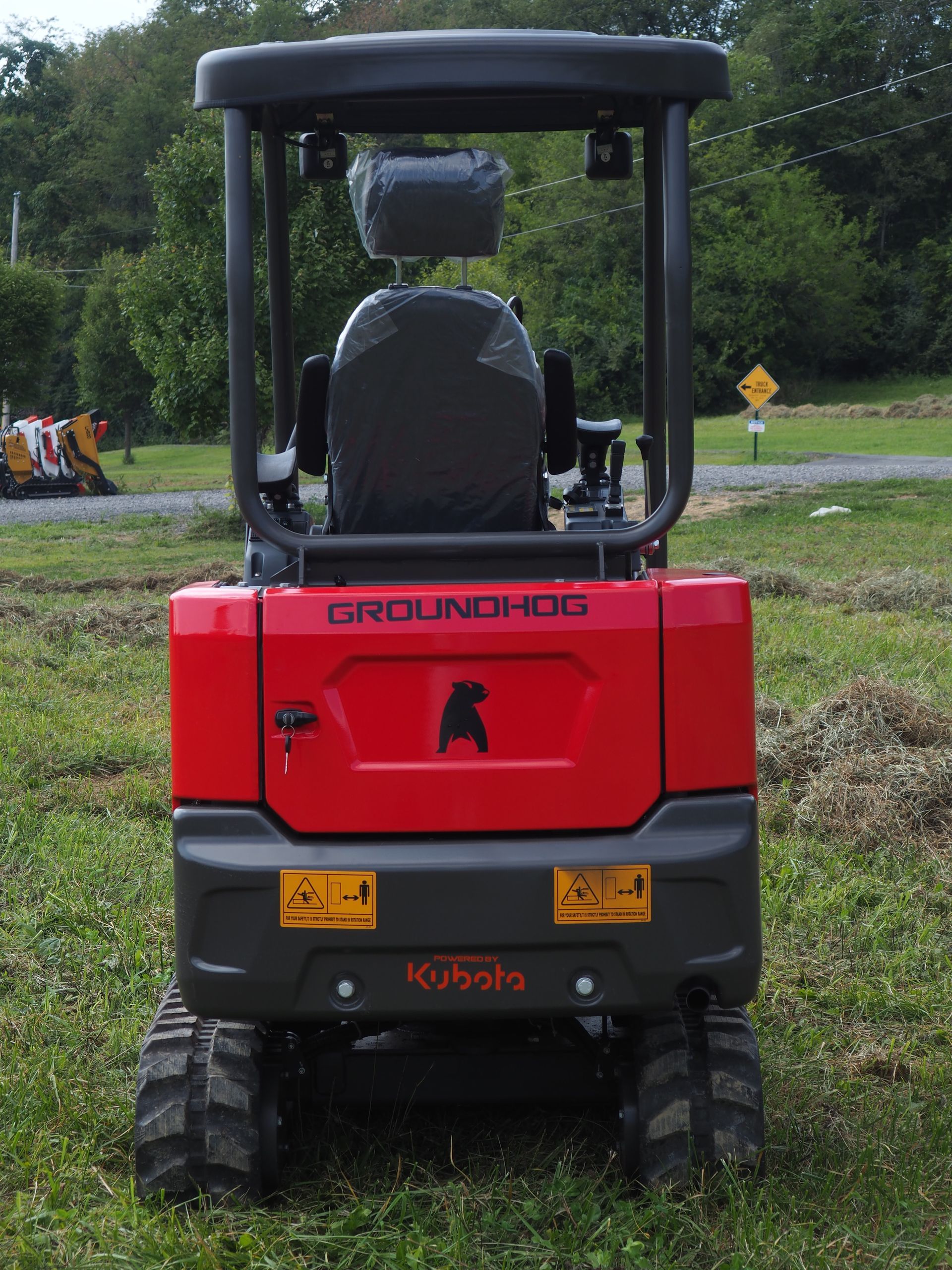 Rear view of a red Groundhog excavator with a Kubota logo on grass.