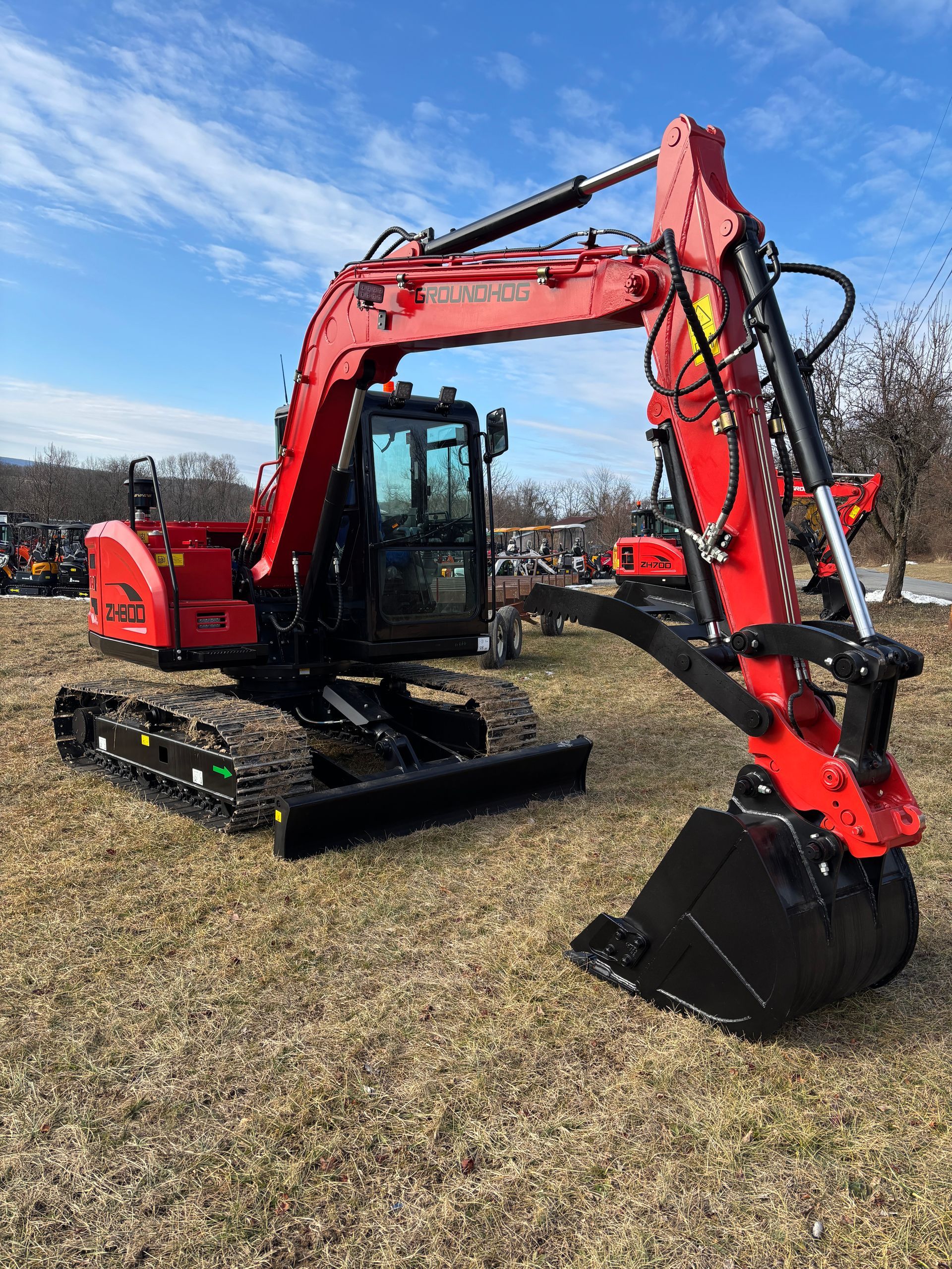 Red excavator on tracks in a field with a blue sky.