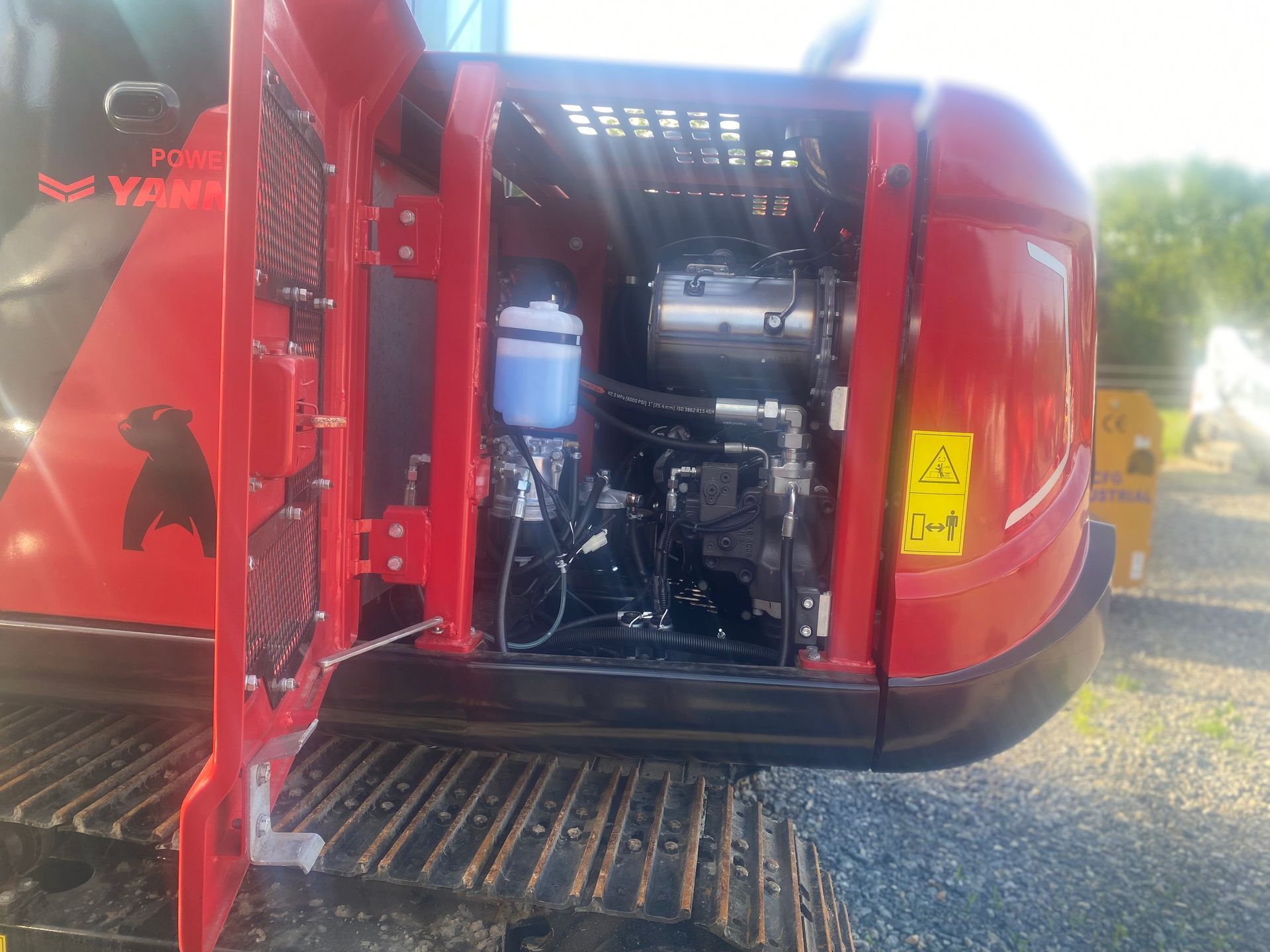 Red Bobcat excavator with its engine compartment open, revealing components.