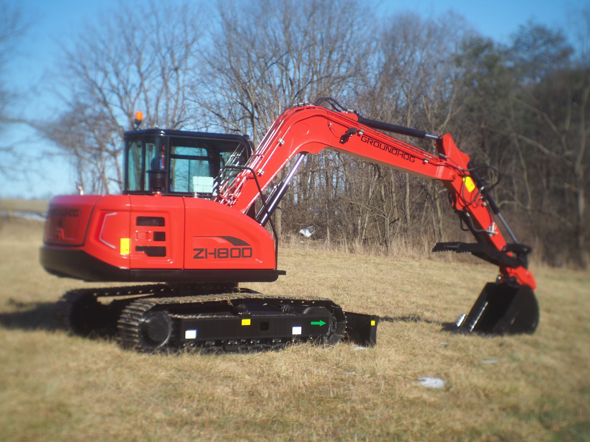 Red excavator on tracks in a grassy field.