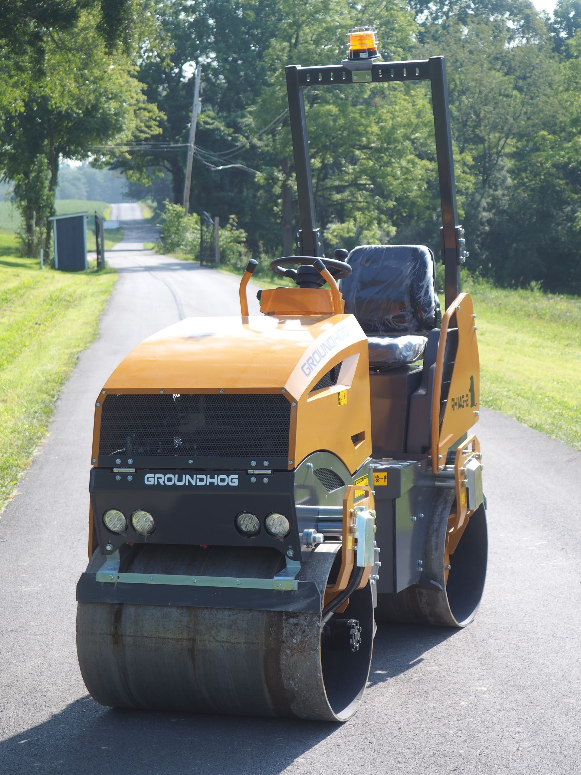 Yellow asphalt roller compacting a black road.