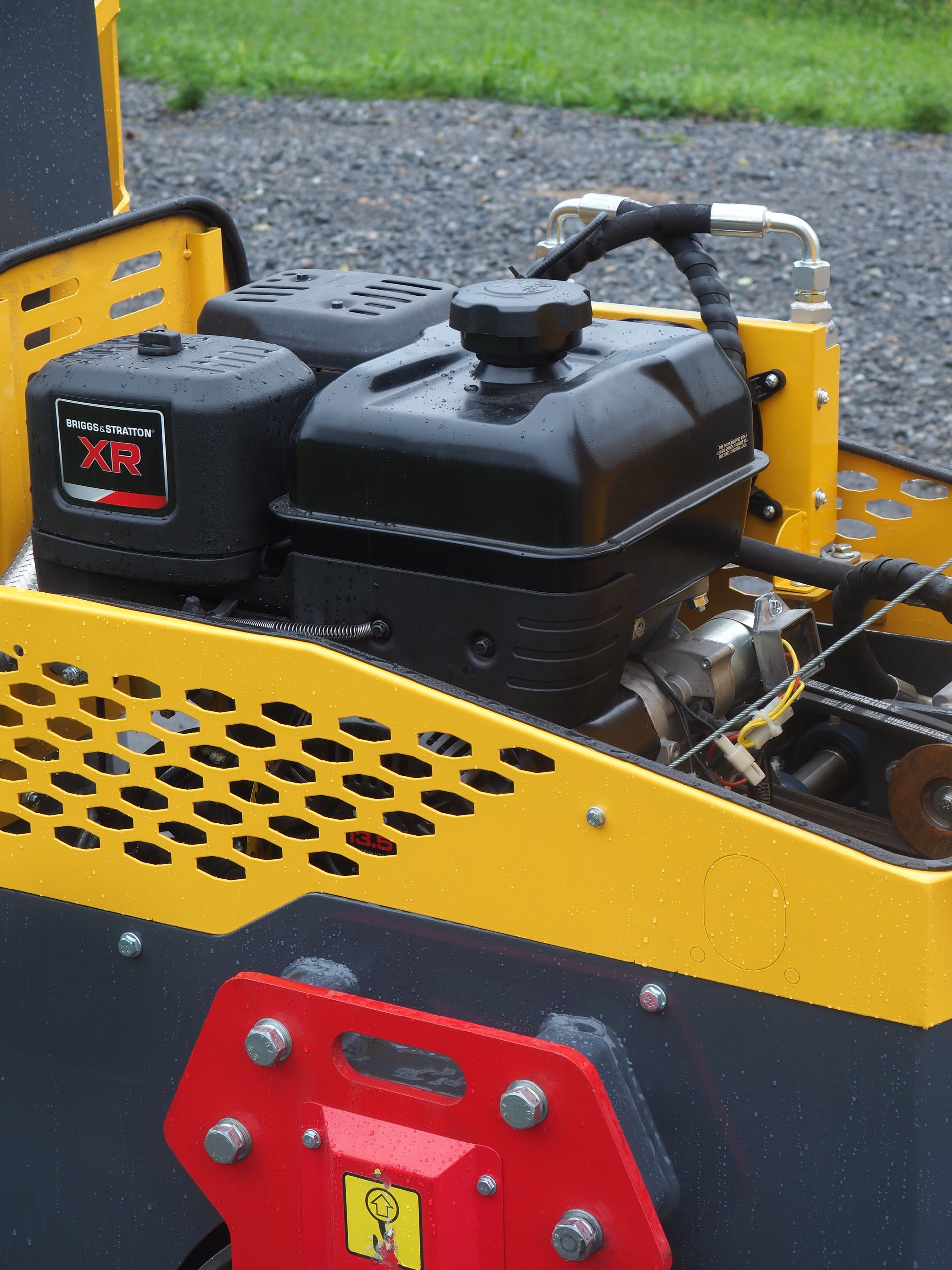Close-up of a yellow and black industrial machine with a black engine and red safety features.