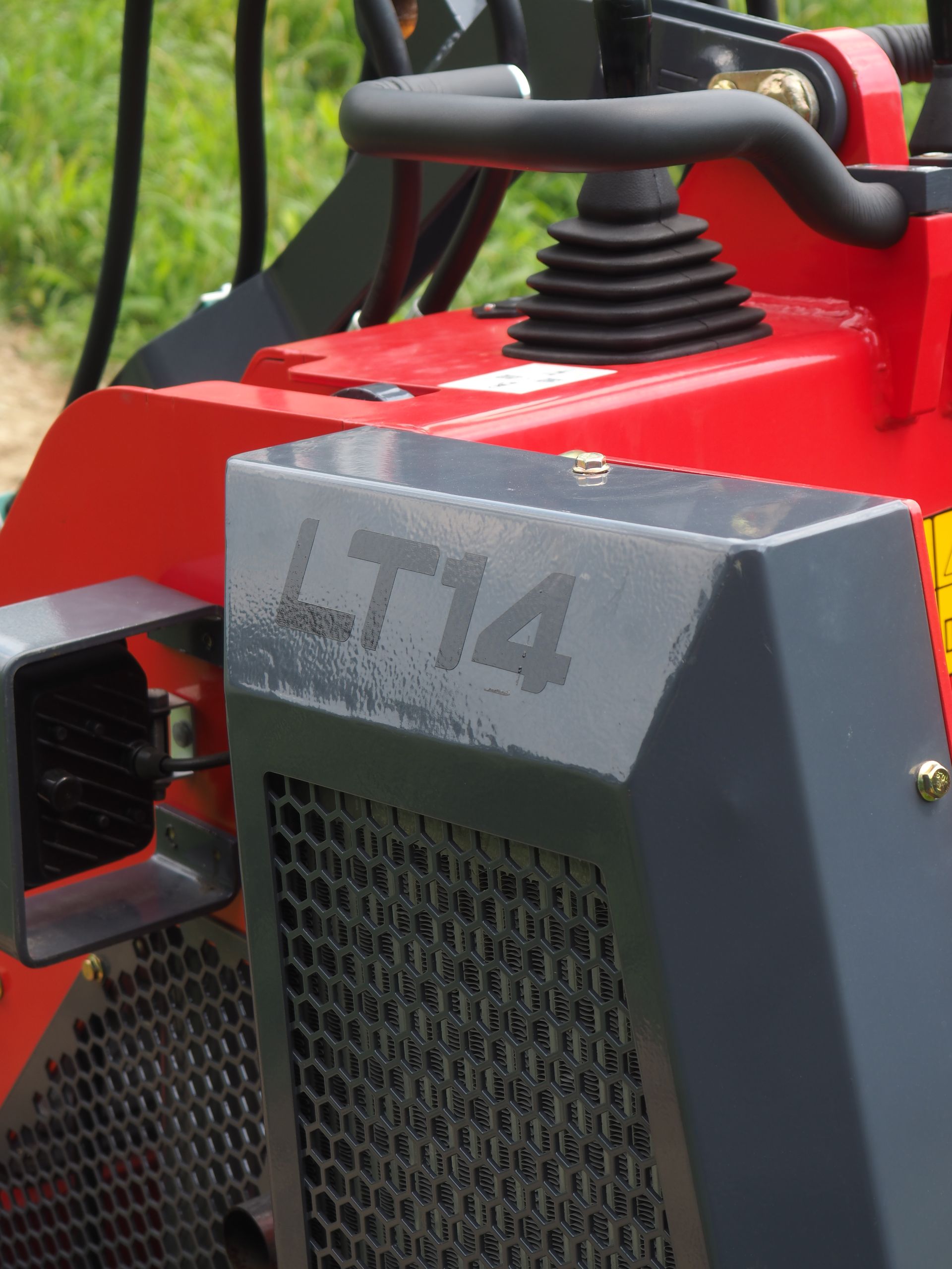 Red and gray LT14 compact machine with a metal mesh grill and a control stick.