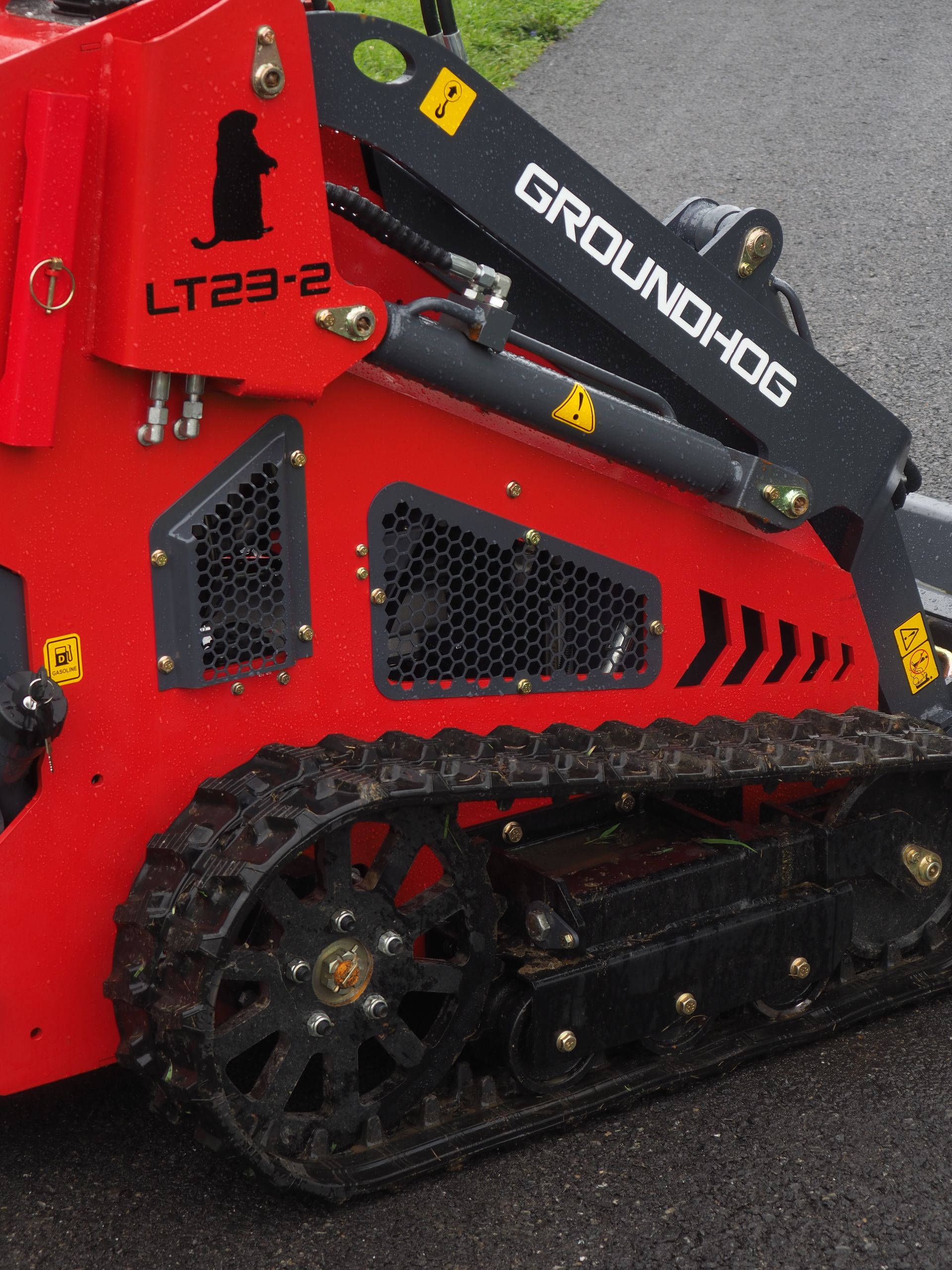 Red and black Groundhog LT23-2 mini skid steer with track wheels, outdoors.