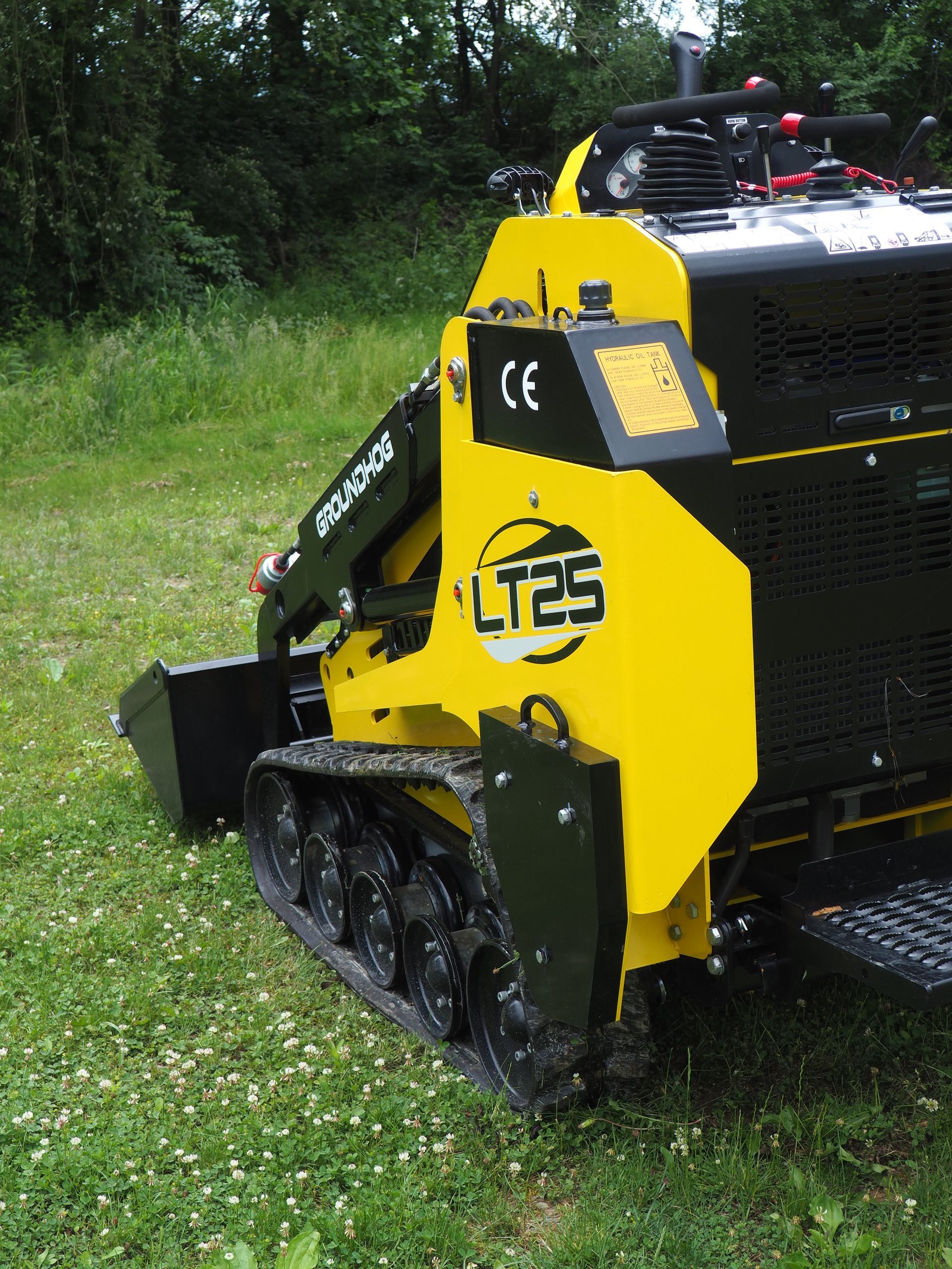 Yellow and black LT25 mini-digger on tracks, operating in a grassy area.