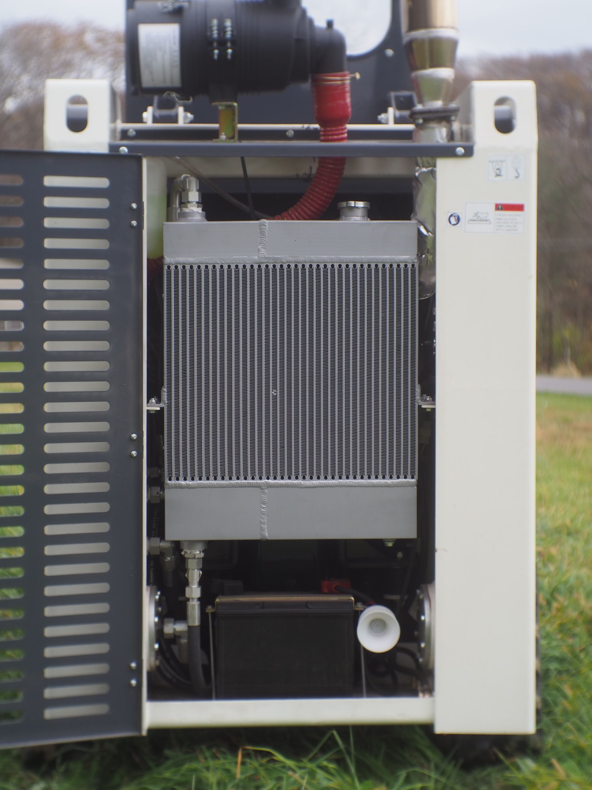 Open machinery cabinet revealing an air compressor with radiator and hoses.