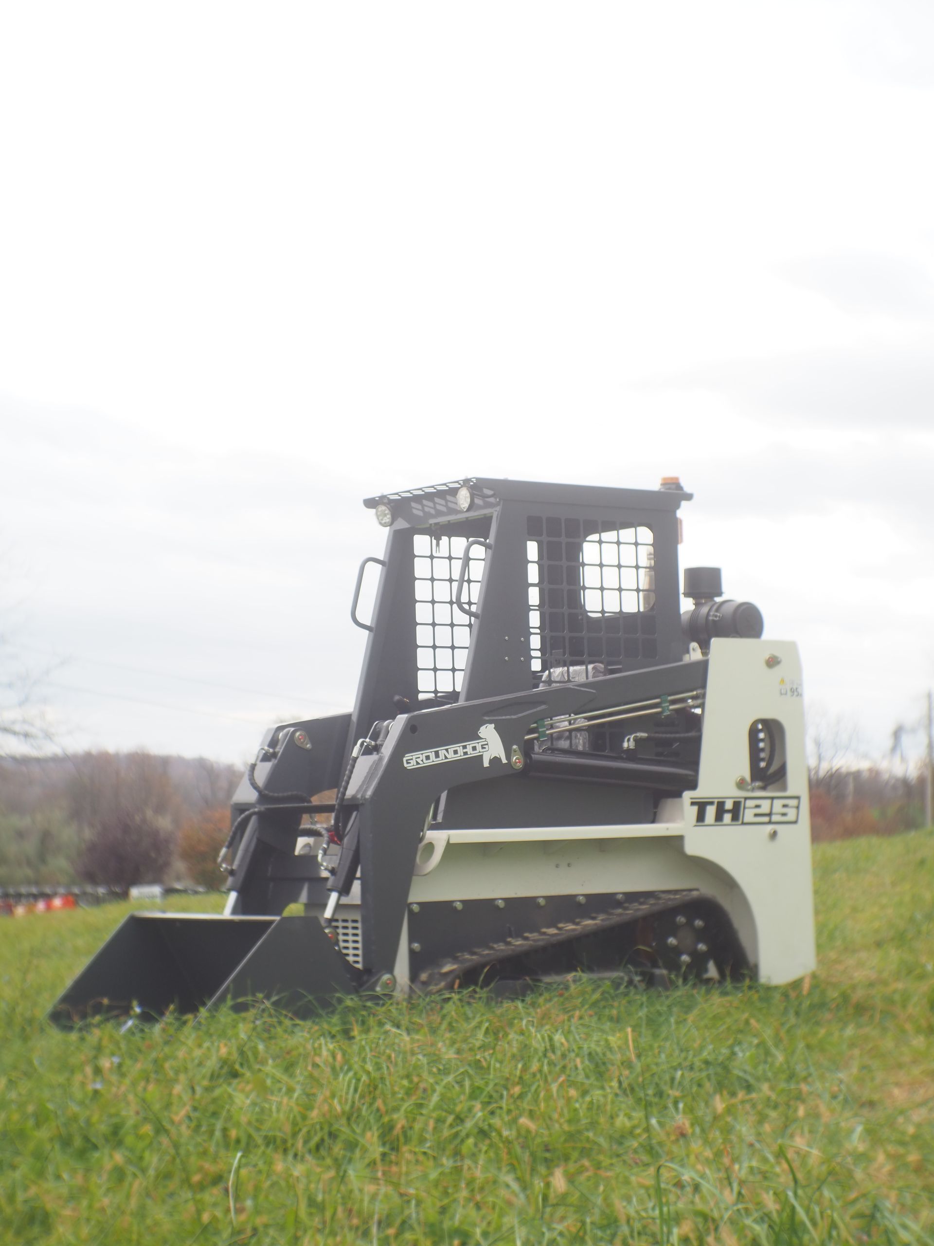 White and black Kubota track skid steer on a grassy field.