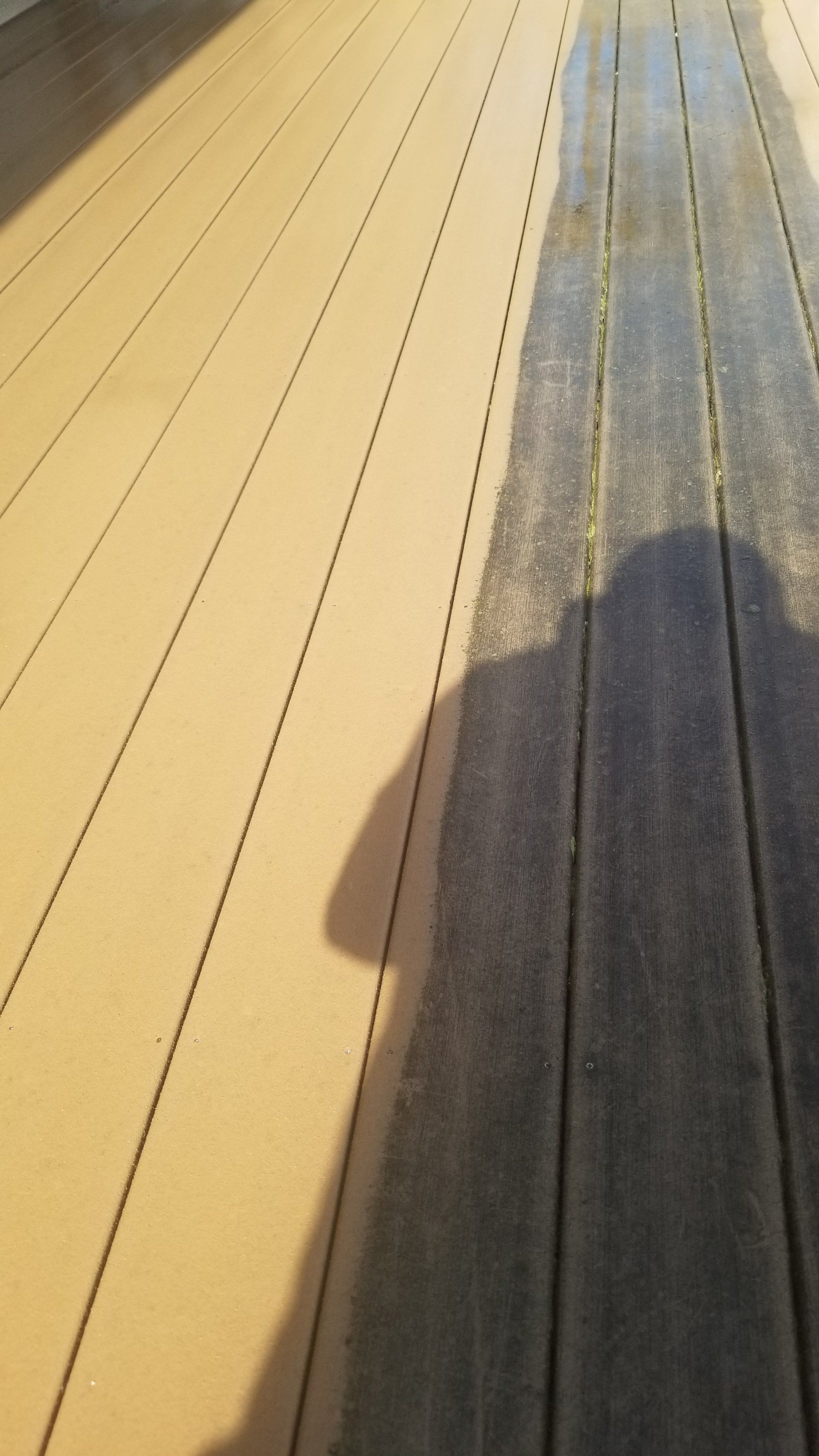 A shadow of a person is cast on a wooden deck.
