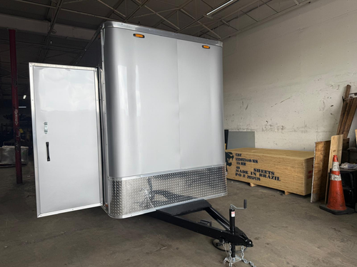 White enclosed cargo trailer with an open side door in a warehouse garage.