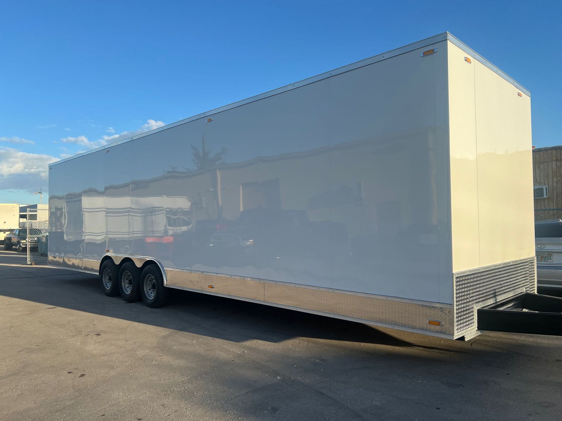White enclosed cargo trailer parked on asphalt under a clear blue sky
