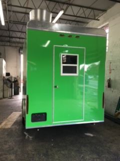 Bright green industrial trailer with a door and window inside a warehouse