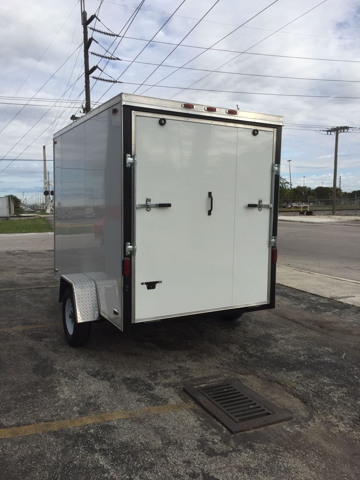 White enclosed cargo trailer parked on asphalt under a cloudy sky