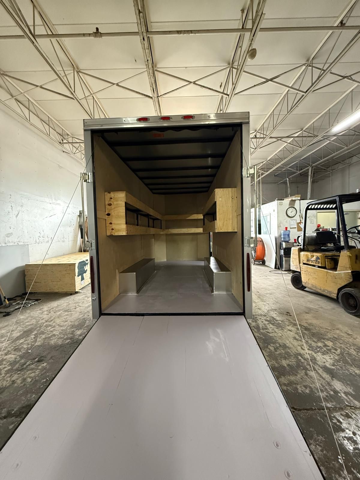 Loading dock with an open box truck backed to a white ramp inside a warehouse.