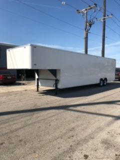 White enclosed semi-trailer parked on a lot under a blue sky, with utility poles in the background