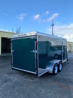Black enclosed dual-axle cargo trailer parked outdoors under a blue sky
