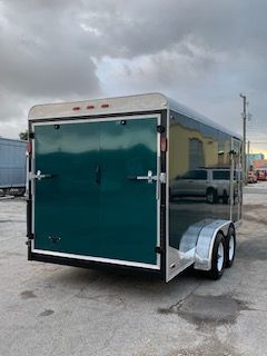Teal enclosed cargo trailer parked outdoors on a cloudy lot
